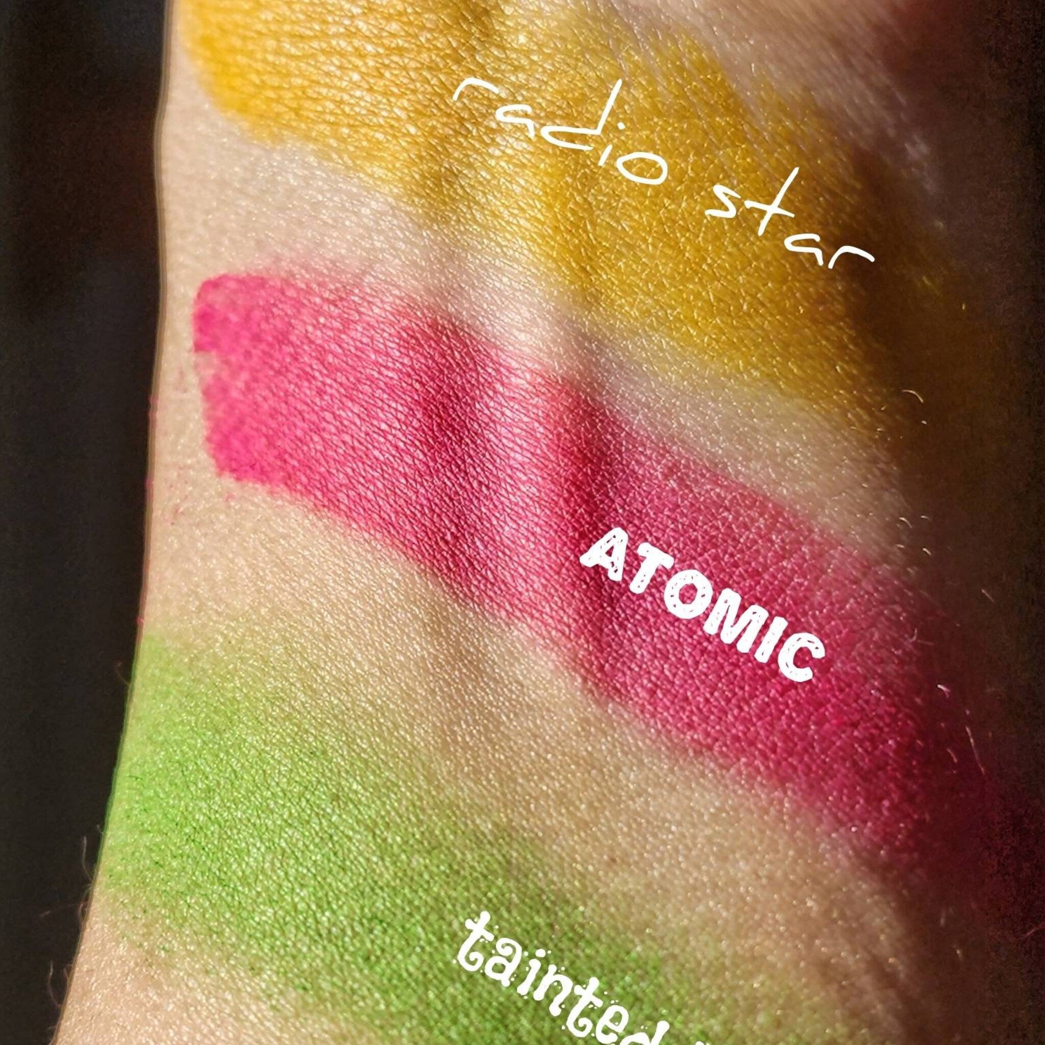 Side view of vegan matte neon yellow eyeshadow pan with 80s-inspired pressed powder texture in compact