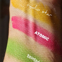Side view of vegan matte neon yellow eyeshadow pan with 80s-inspired pressed powder texture in compact