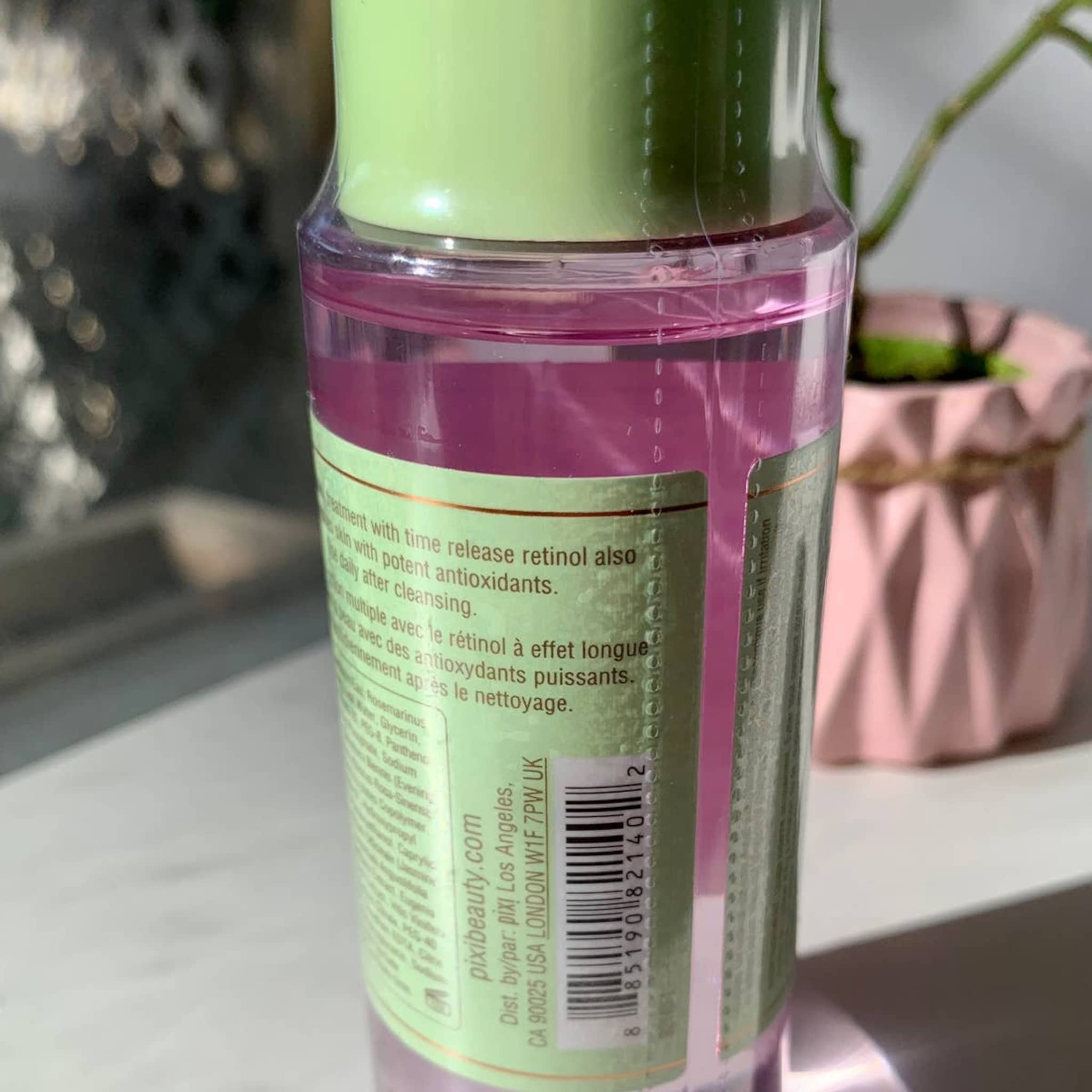 Retinol treatment bottle with pink liquid, green label, and clear plastic, Pixi brand visible