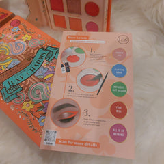 Makeup palette with orange, teal, and gold floral design, and J.Cat Beauty instructions on how to use