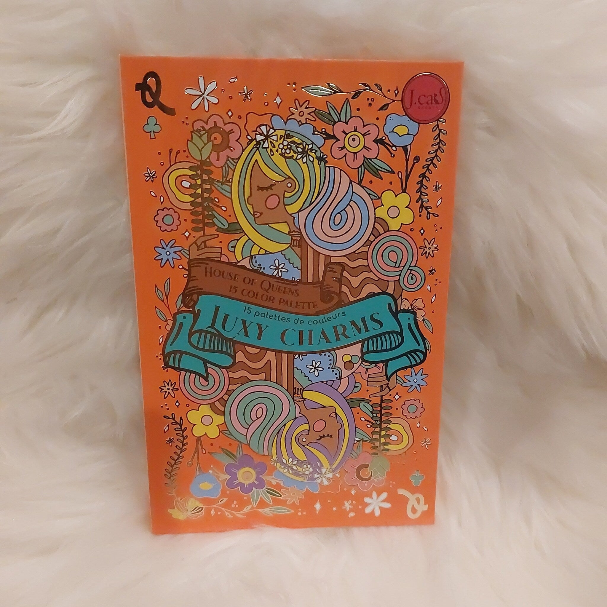 Eye shadow palette with orange background, floral design and J.Cat Beauty branding on the front cover.