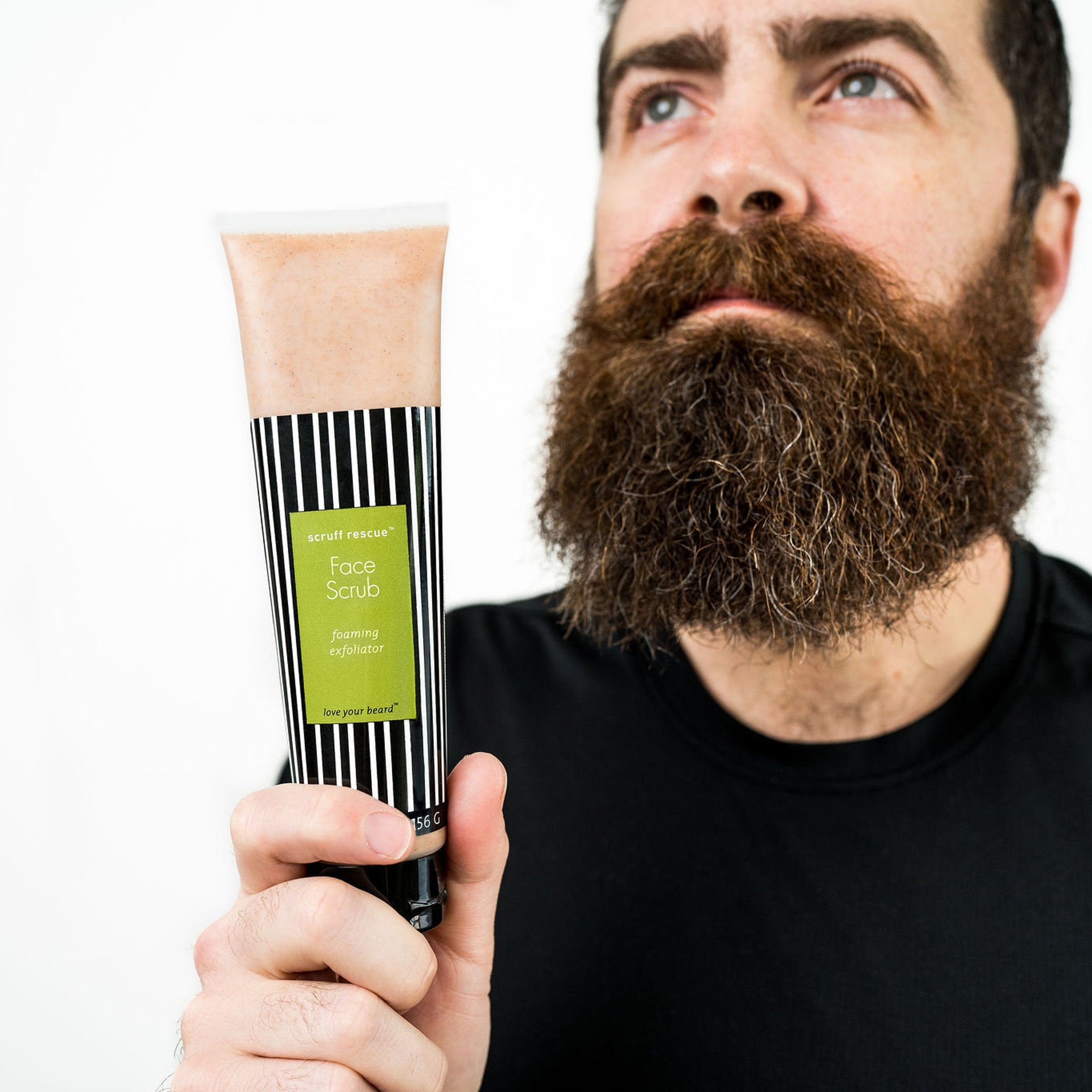 Face scrub tube with black and white striped pattern, green label, held by a man