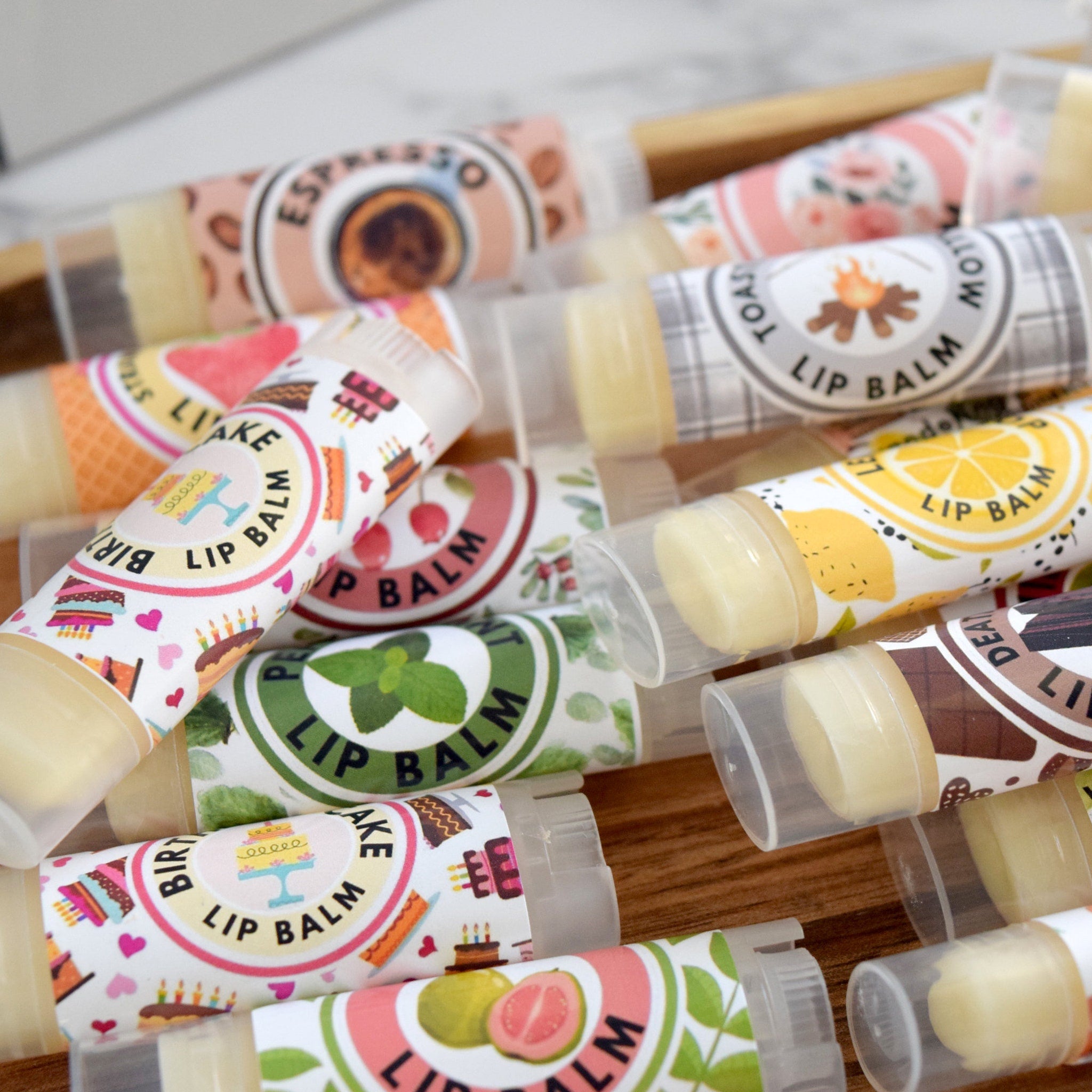 Lip balm tubes with various label designs, clear plastic tubes, and beige balm inside