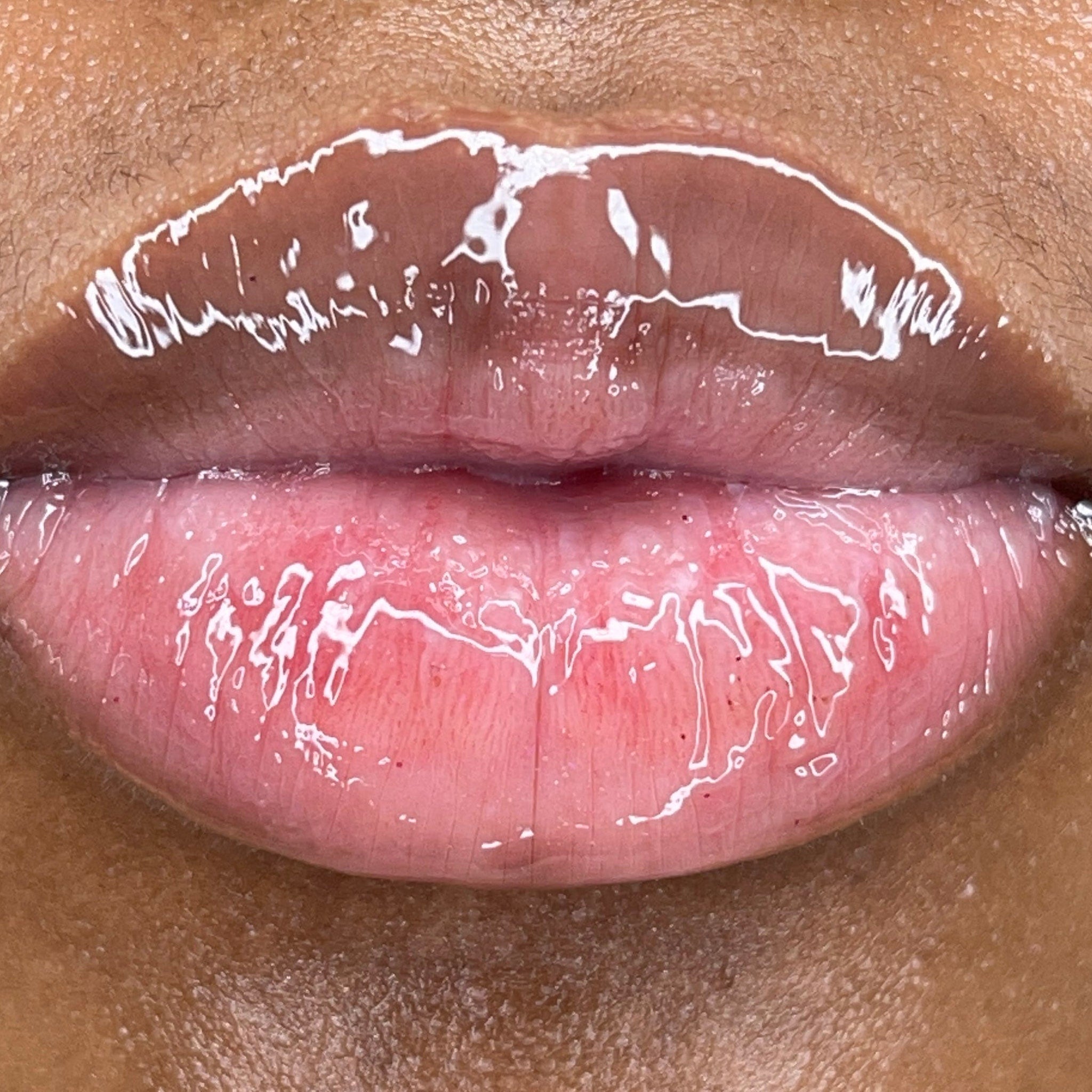 Lip gloss with clear, glossy finish and pink undertones on lips