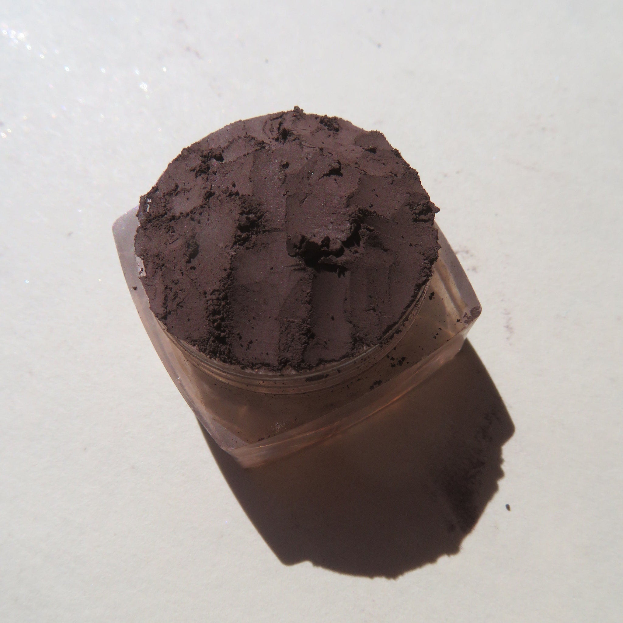 Close-up of rich mahogany loose pigment powder being applied as eyeliner with a thin angled brush