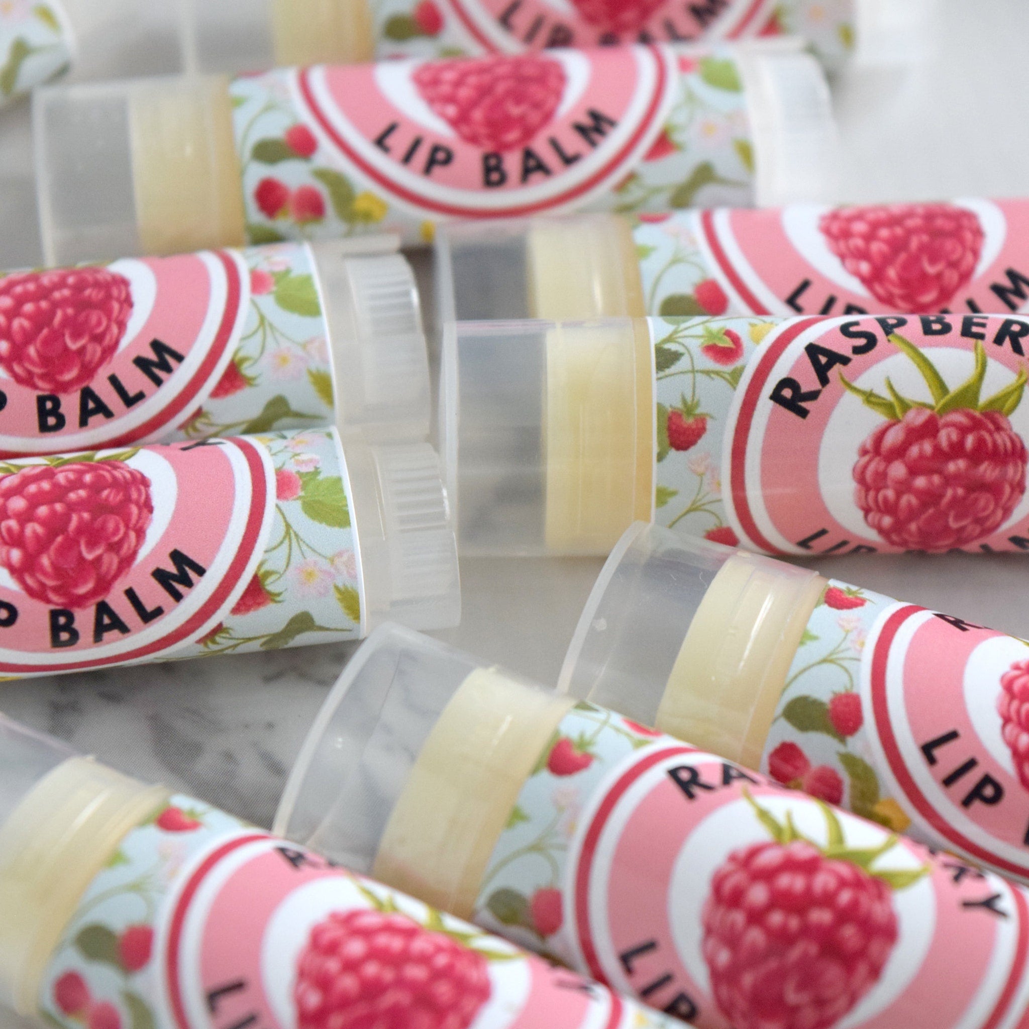 Lip balm tubes with pink and floral labels, clear plastic caps, and visible text