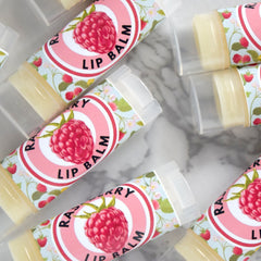 Lip balm tubes with raspberry labels, floral pattern, and clear plastic caps