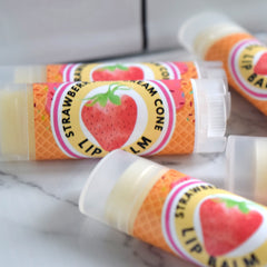 Lip balm tubes with strawberry design, clear plastic, and yellow balm inside