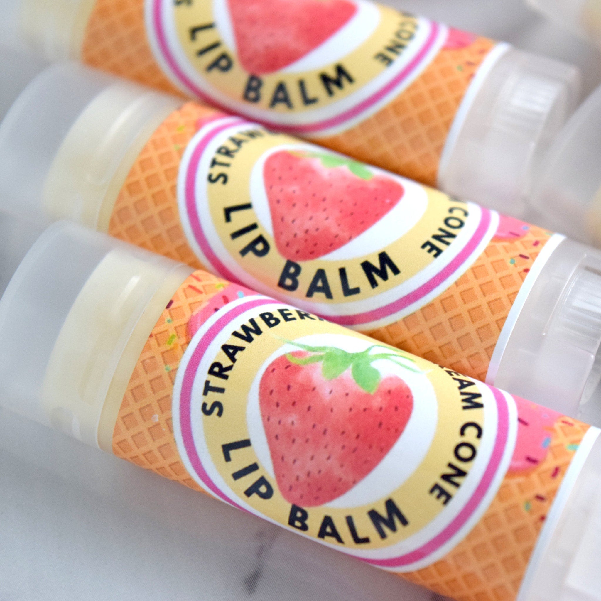Lip balm tubes with strawberry design, white plastic cap, and waffle cone pattern
