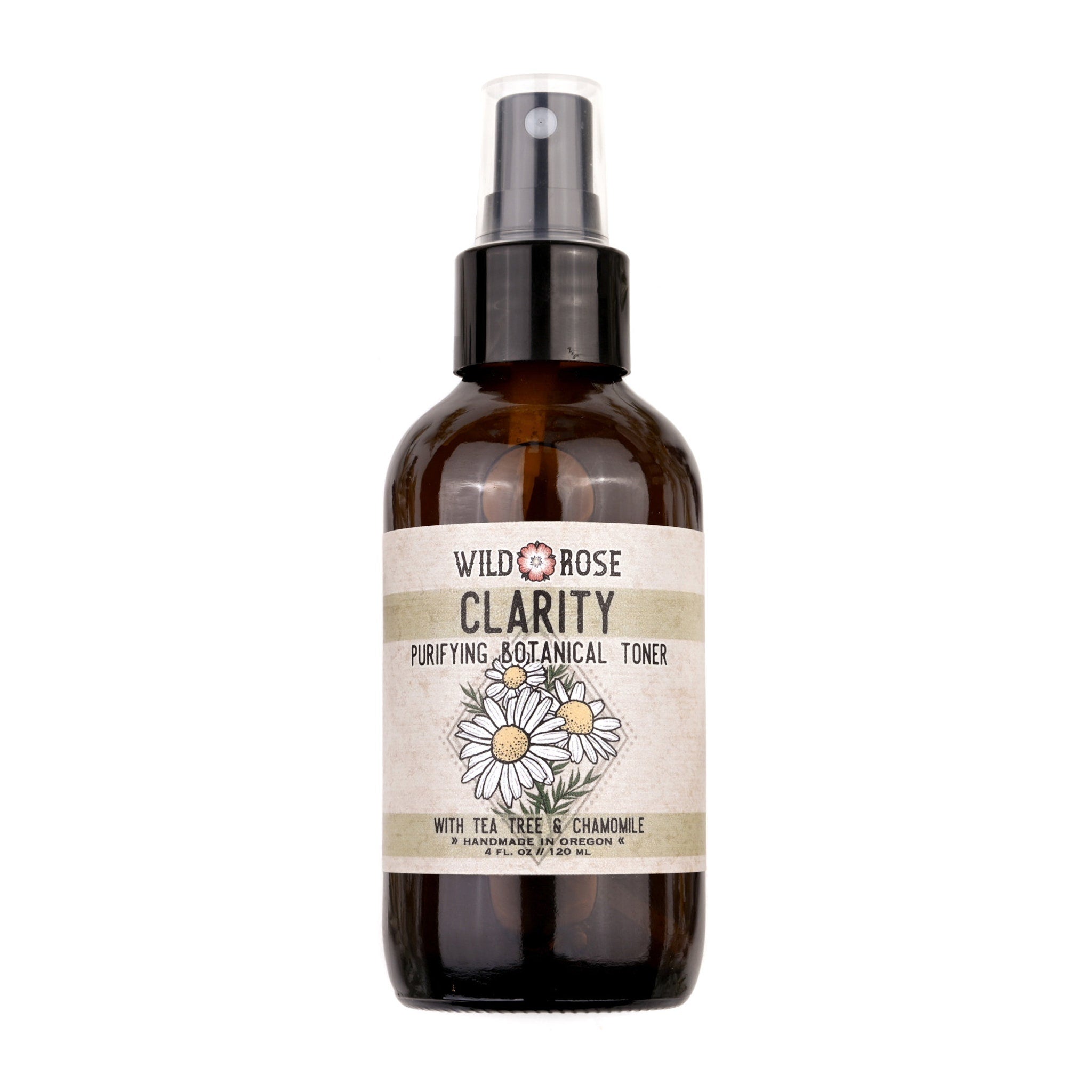 Botanical toner spray bottle with brown glass, white label, and black pump top featuring Wild Rose Clarity text