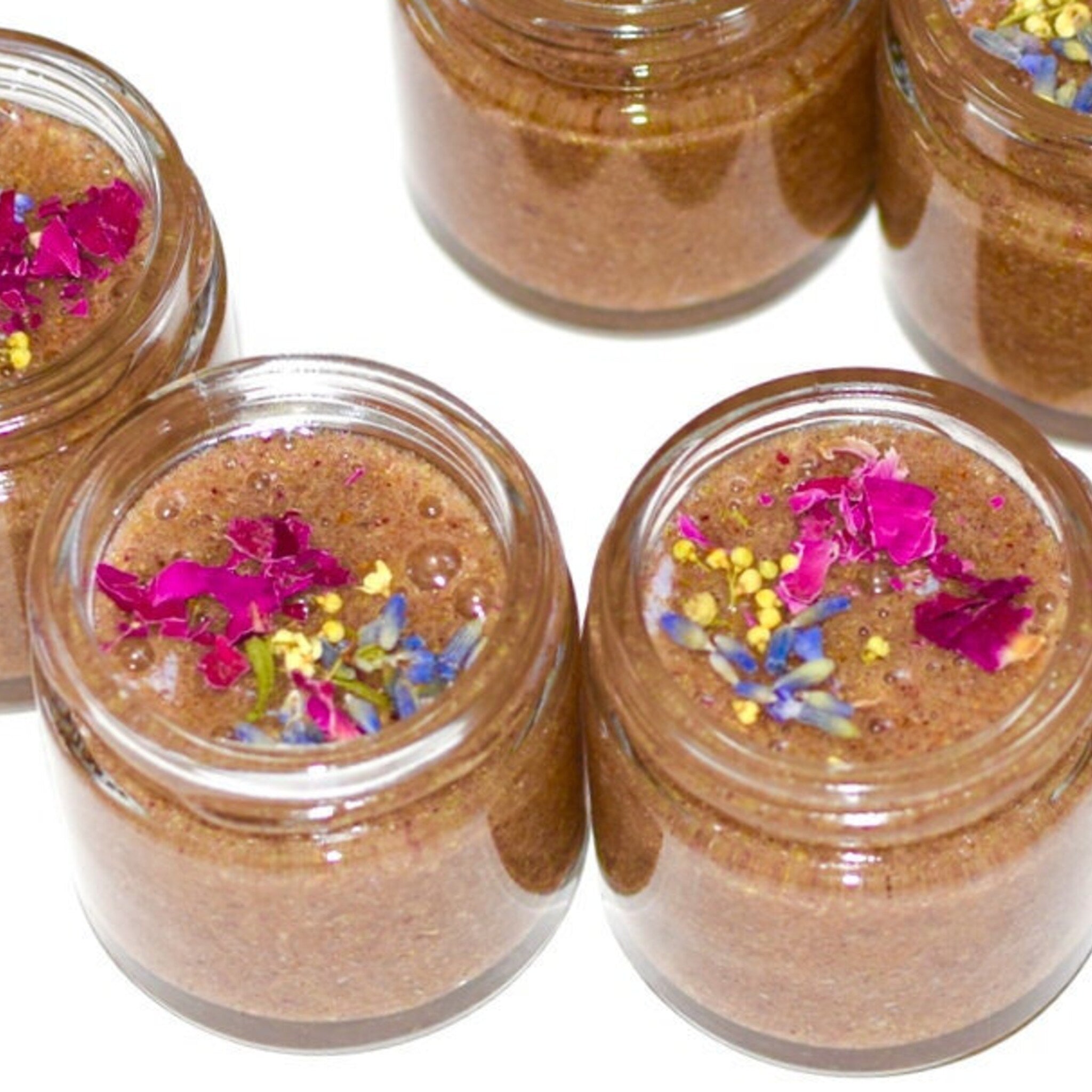 Honey scrub in glass jars, brown and pink floral accents, skincare product