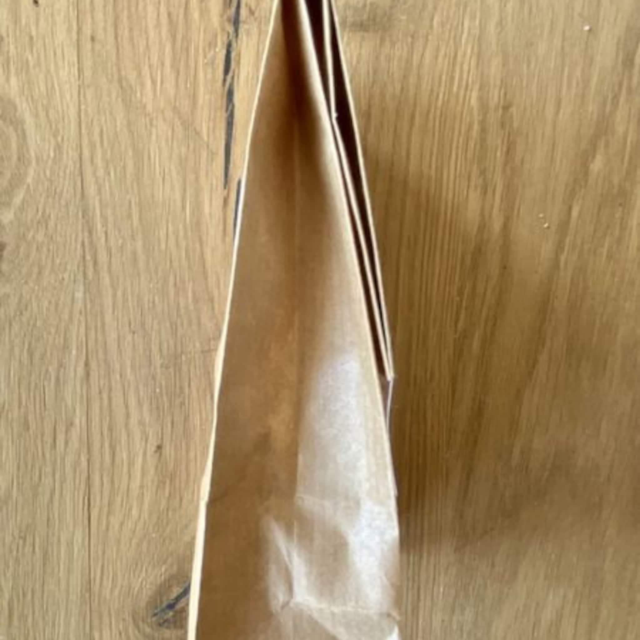 Brown paper bag with folded top, against a wood grain background