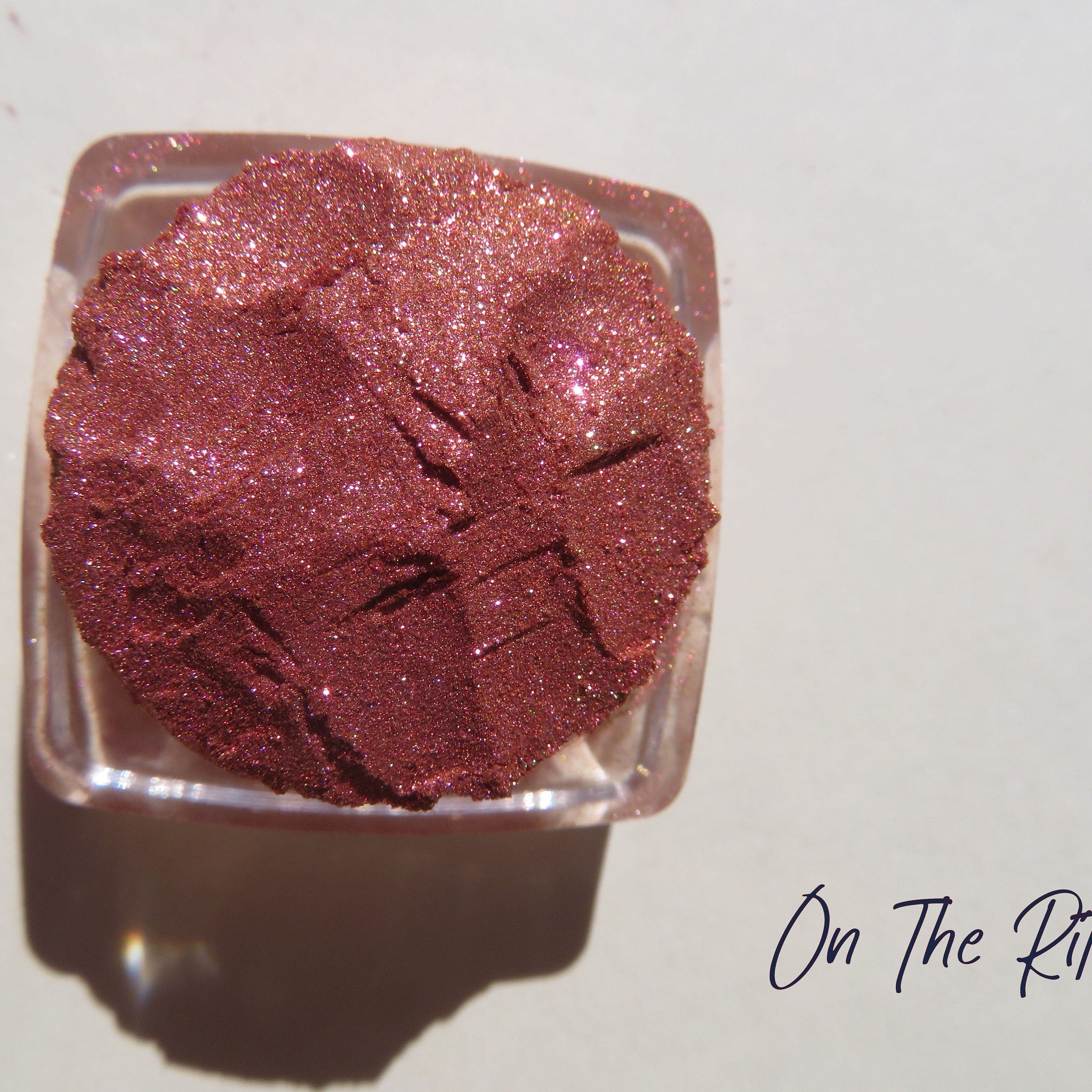 Shimmering loose mineral eyeshadow in orange-pink-gold tones with vegan, carmine-free formula in a small jar