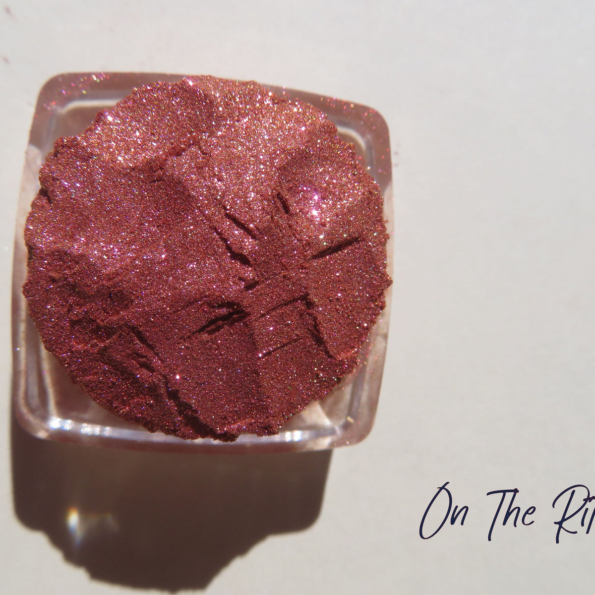 Shimmering loose mineral eyeshadow in orange-pink-gold tones with vegan, carmine-free formula in a small jar