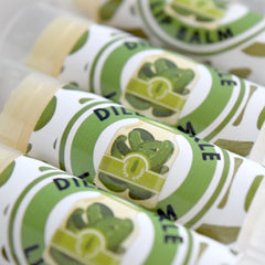 Lip balm tubes with white, green, and black labels, showing "Dill Pickle" text and pickle illustration.