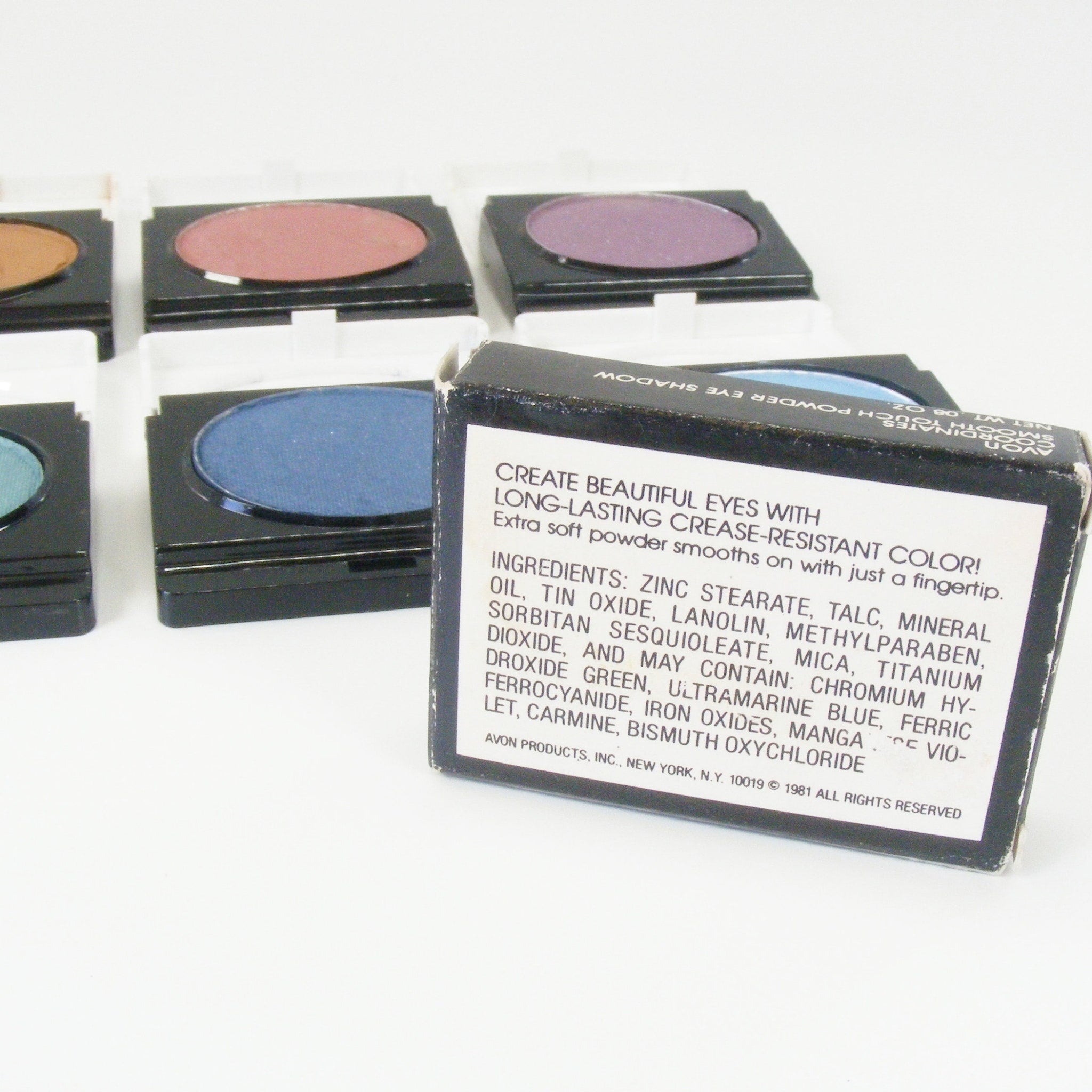 Eyeshadow compacts in various colors, black plastic case, Avon branding visible on box