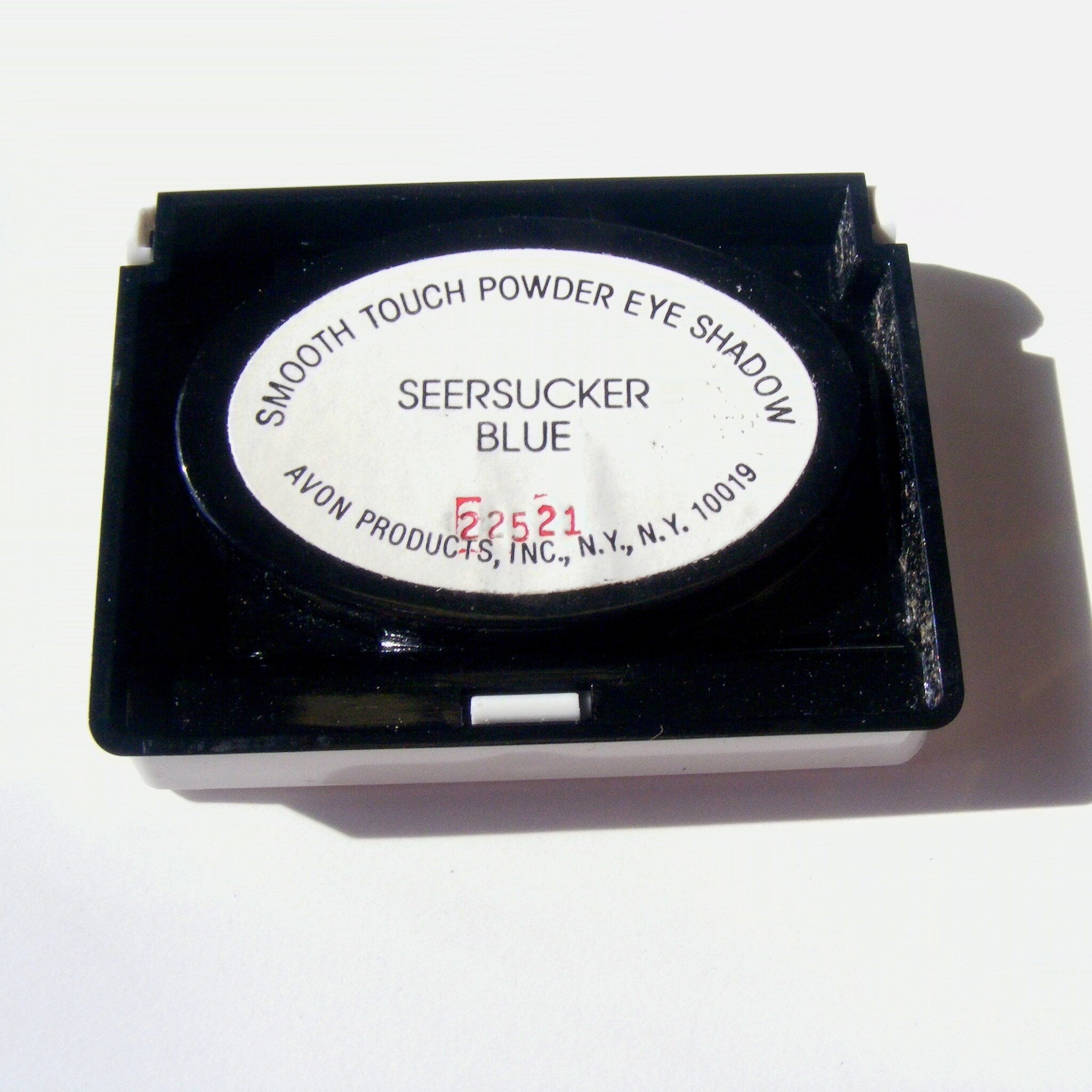 Powder eye shadow compact in black and white with Avon text and blue color label