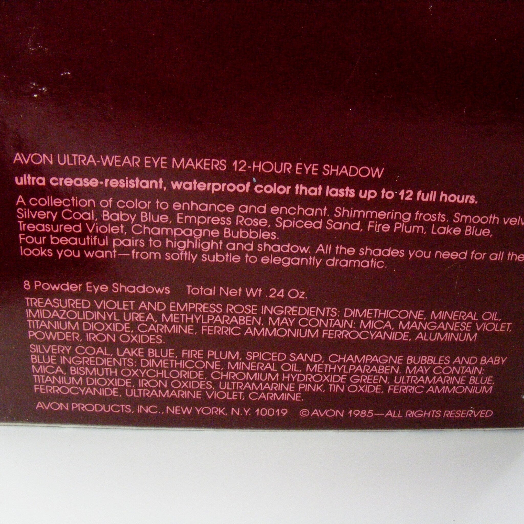 Close-up of fingertips applying shimmering taupe eyeshadow from compact onto eyelid