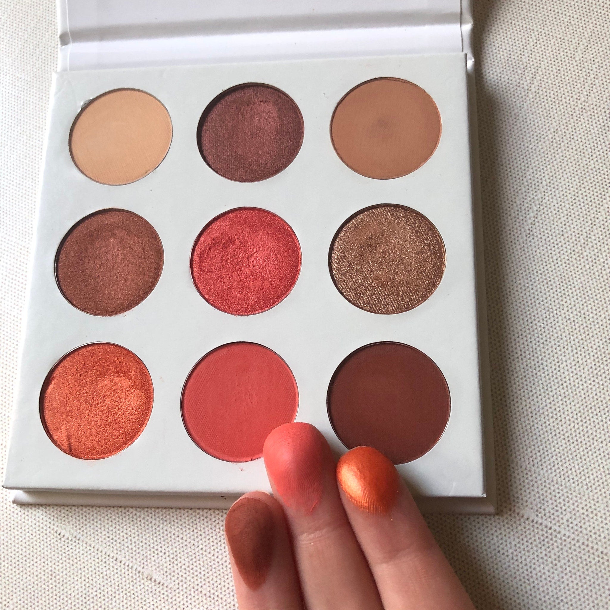 Side view of Red Daisies Eye Shadow Palette showing six vibrant powder shades in circular pans with floral imprint designs