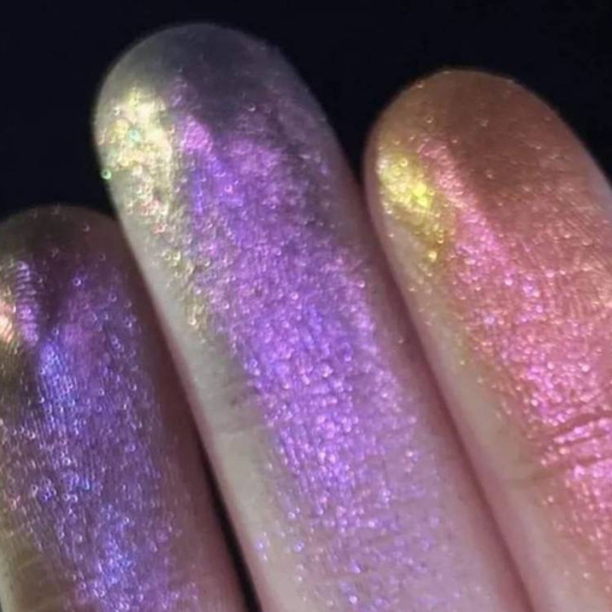 Close-up of pressed eyeshadow pan showcasing purple-olive chameleon shimmer with magical color shift sparkle