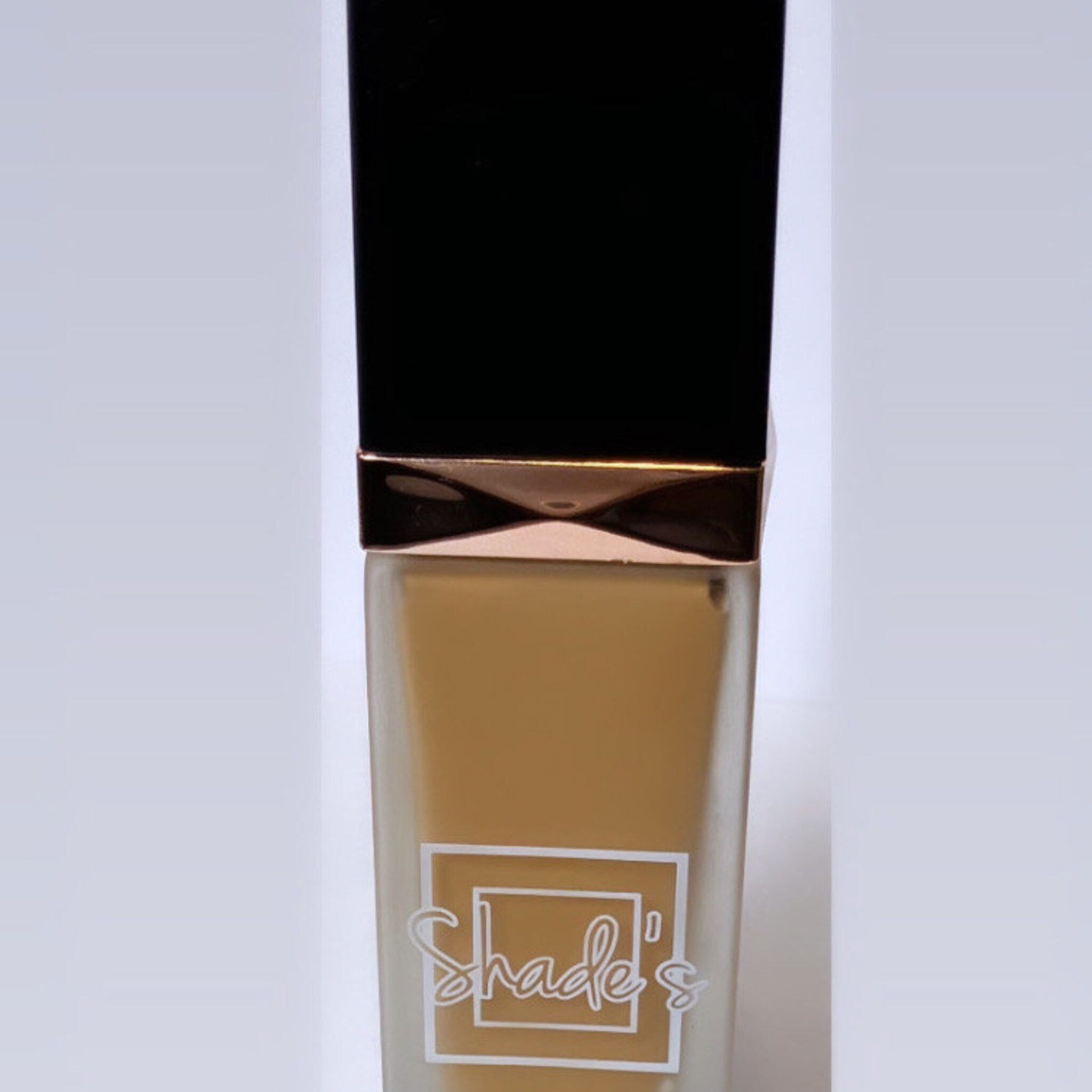 Close-up of fingertips applying shimmering taupe eye shadow to eyelid with soft blending brush
