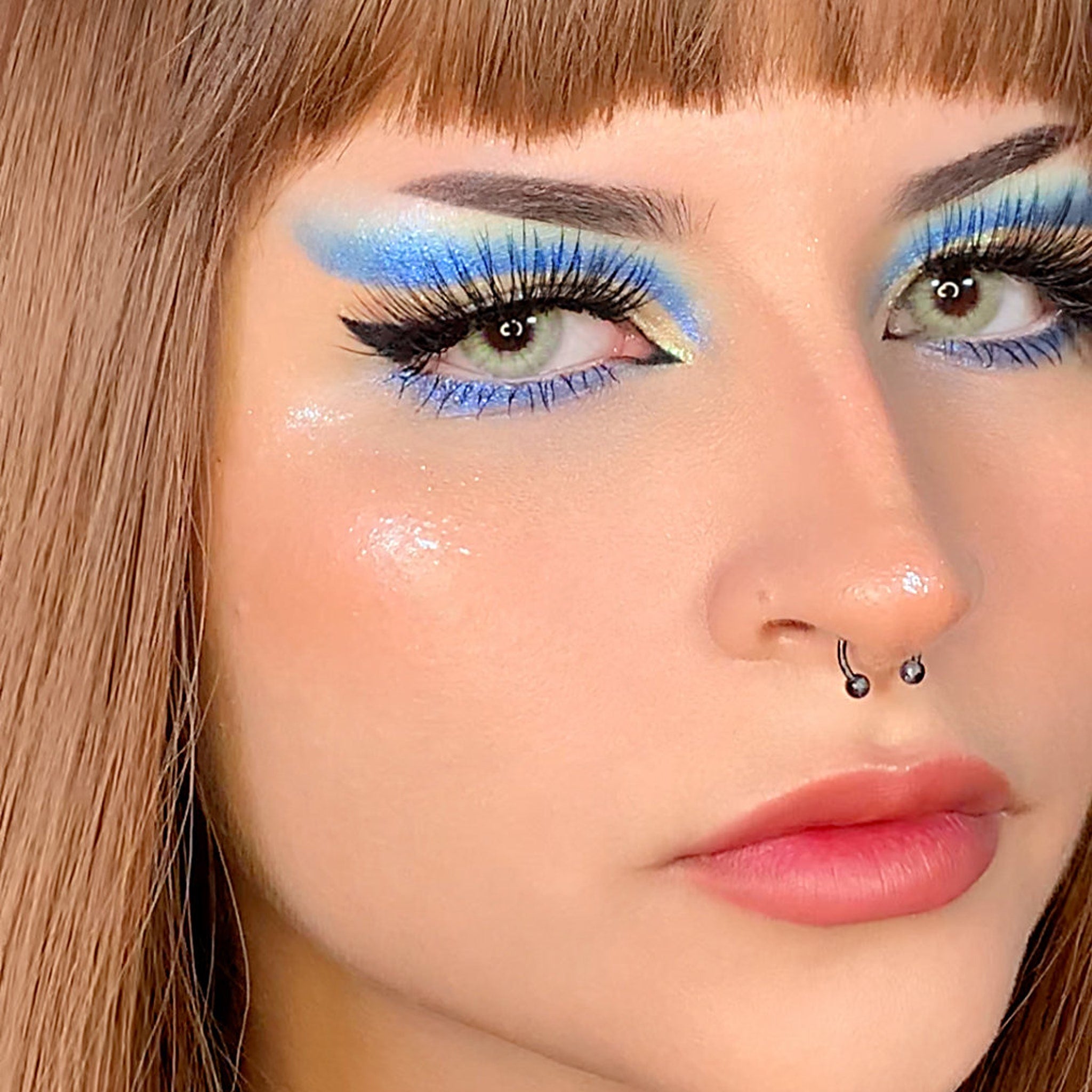 Hand applying multichrome eyeshadow with fingertip, showing vibrant color shift on eyelid
