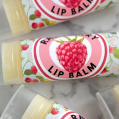 Lip balm tubes with floral pattern, pink and white label, and raspberry graphic