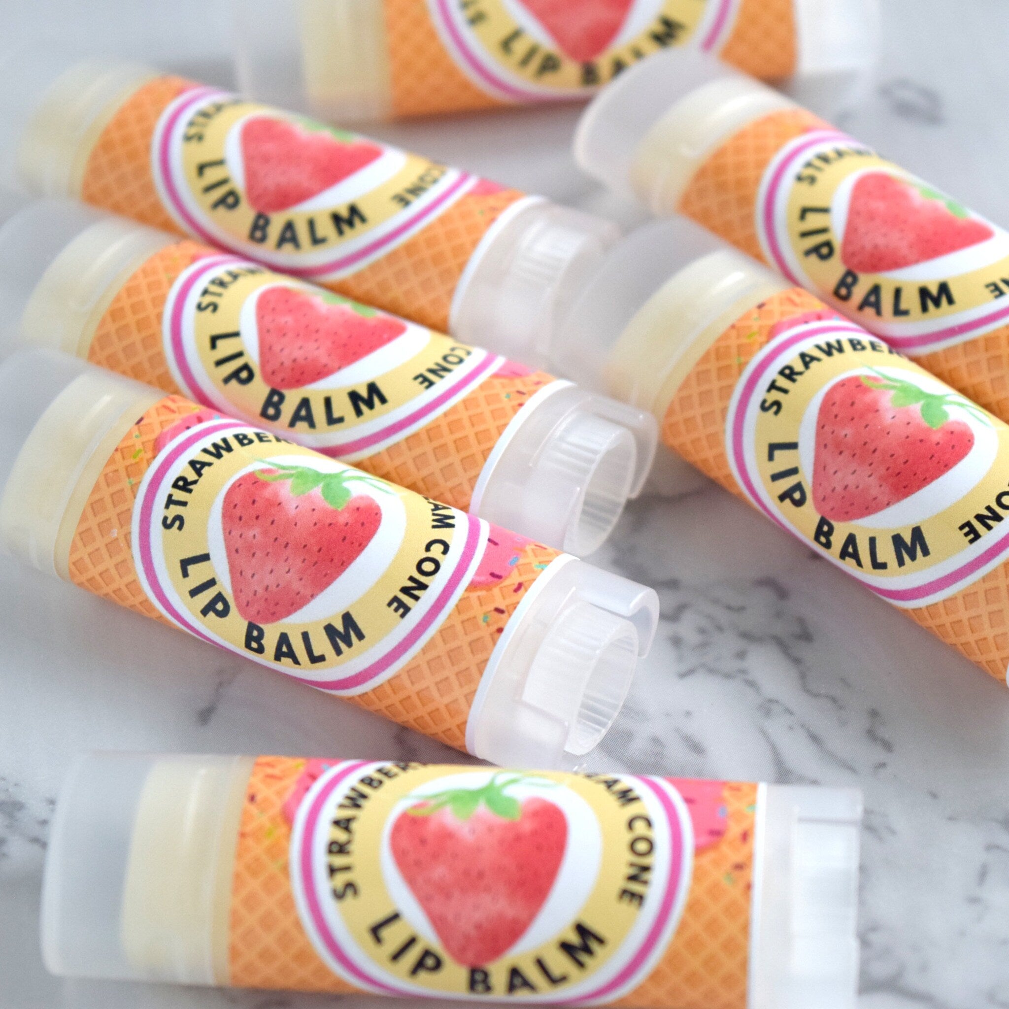 Lip balm tubes with strawberry design, waffle cone pattern, and clear plastic caps