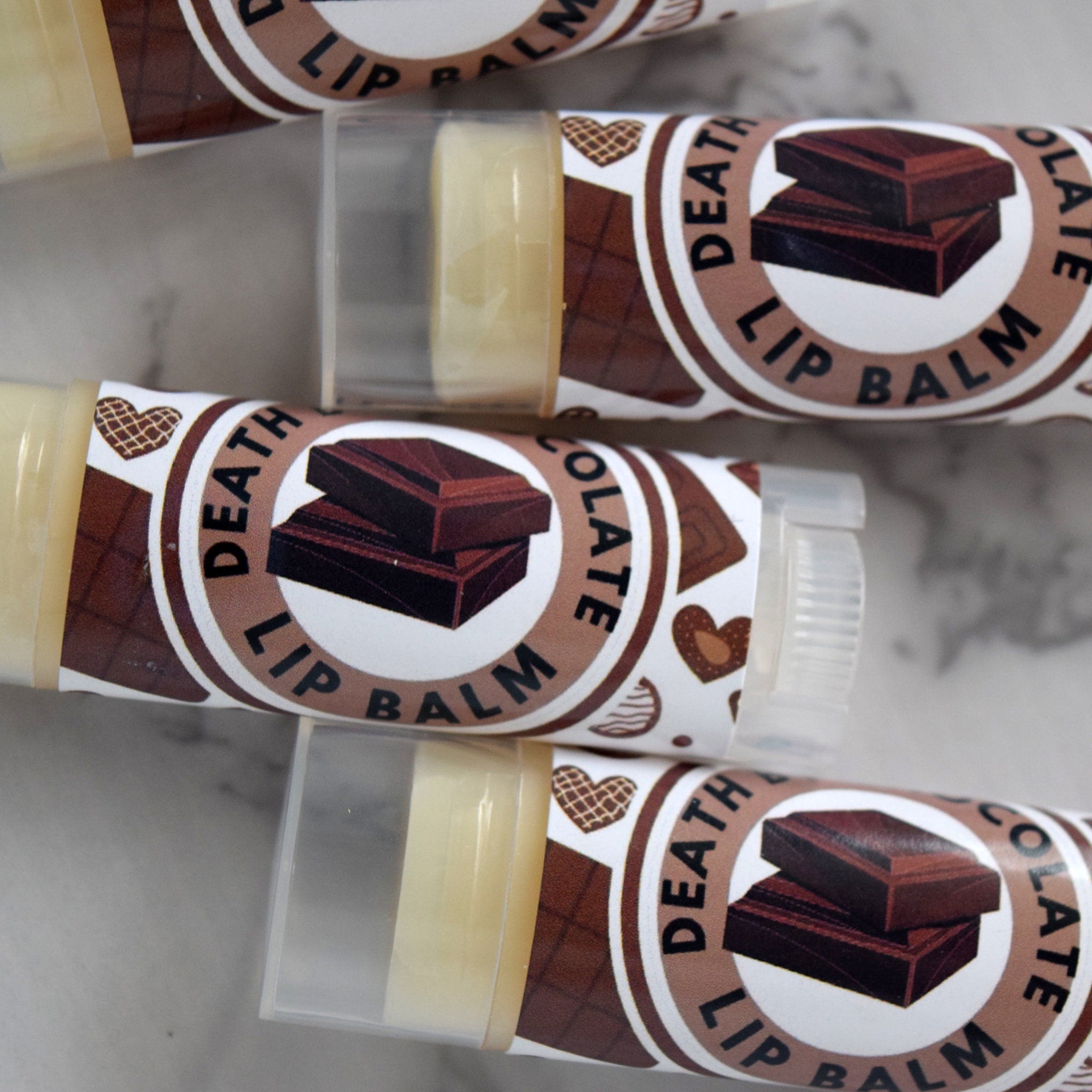Lip balm tubes with brown and white label, "Death by Chocolate" text, and clear plastic cap