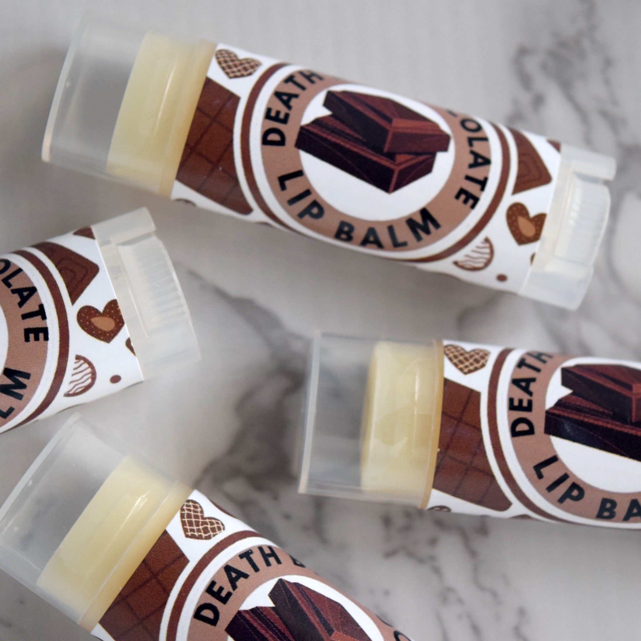 Lip balm tubes with brown patterned labels and clear plastic caps, "Death Lip Balm" text visible
