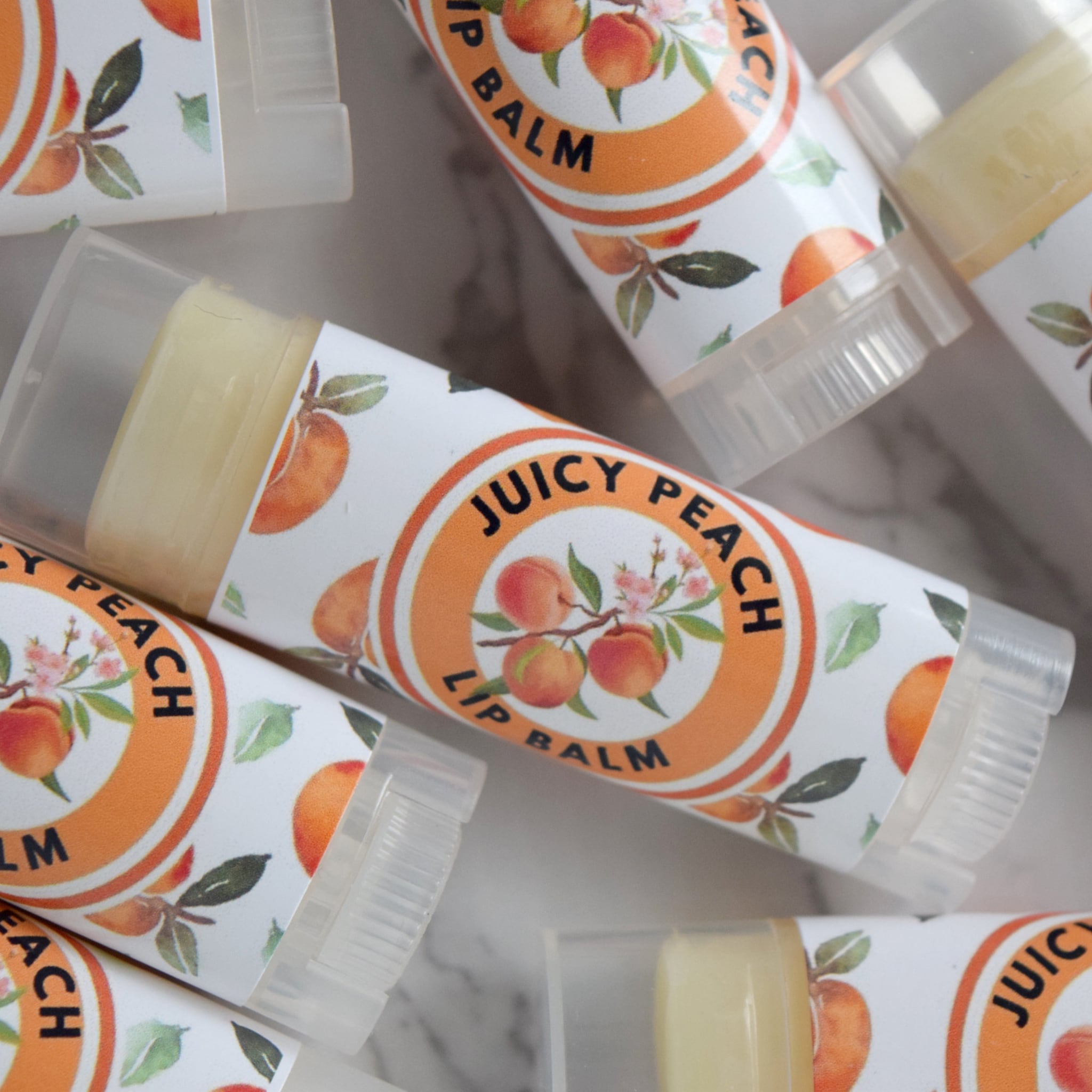 Peach lip balm tubes with peach and floral pattern, clear plastic, and "Juicy Peach" text