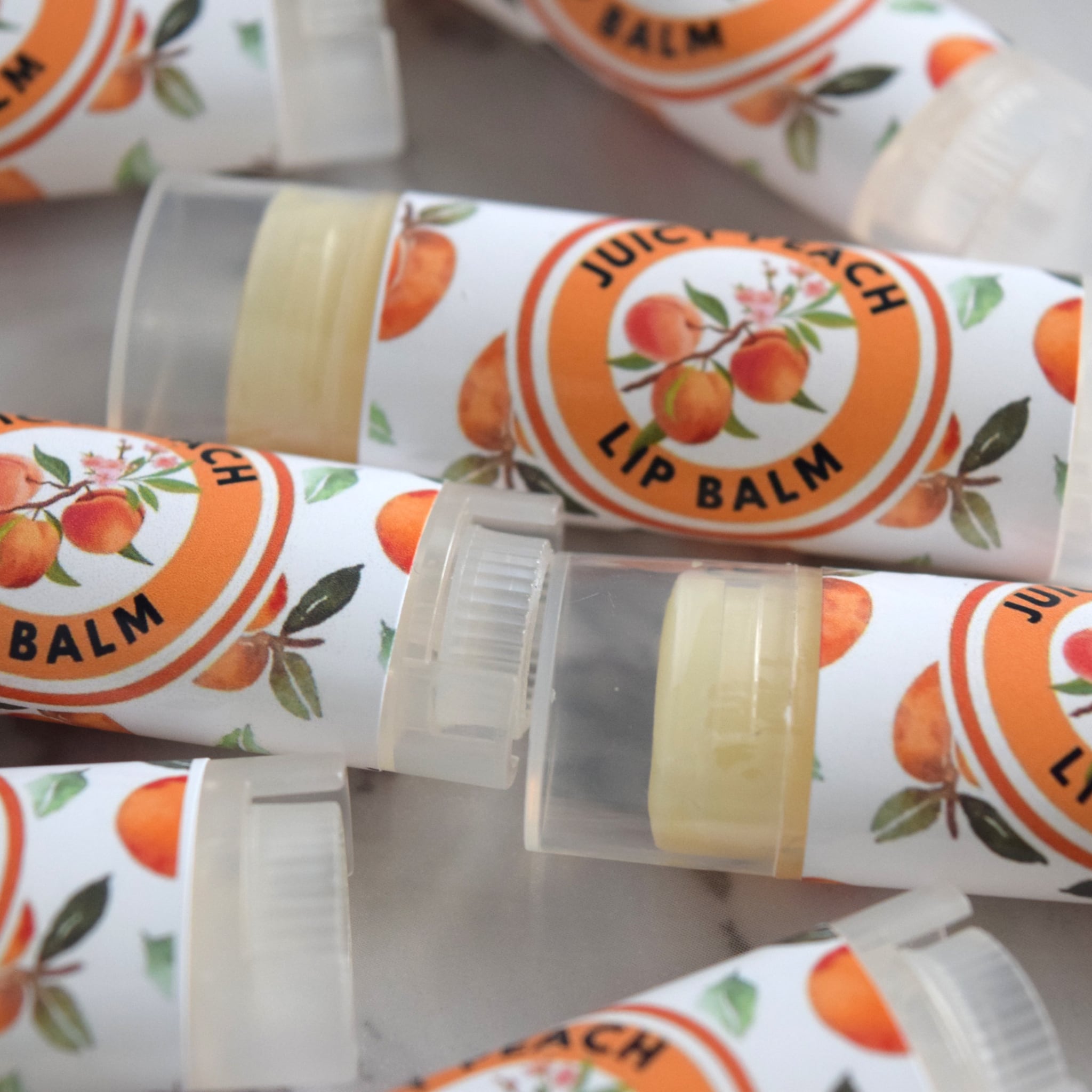 Lip balm tubes with peach fruit pattern and "Juicy Peach" text, clear plastic cap