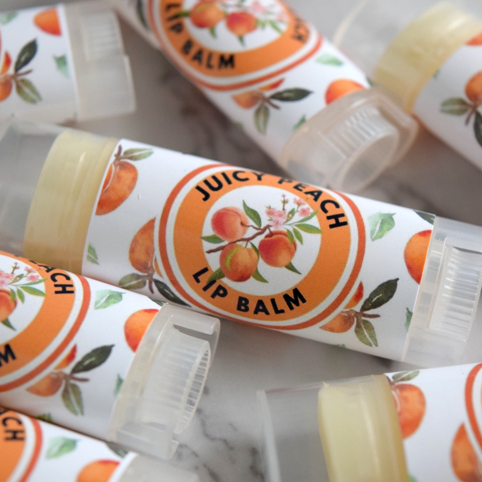 Lip balm tubes with peach pattern, clear plastic cap, and "Juicy Peach Lip Balm" text