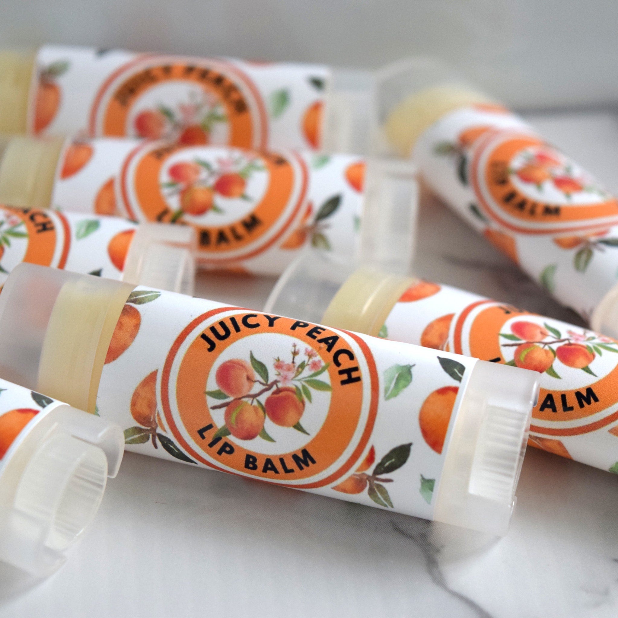 Lip balm tubes with peach fruit pattern and "Juicy Peach" text on white labels