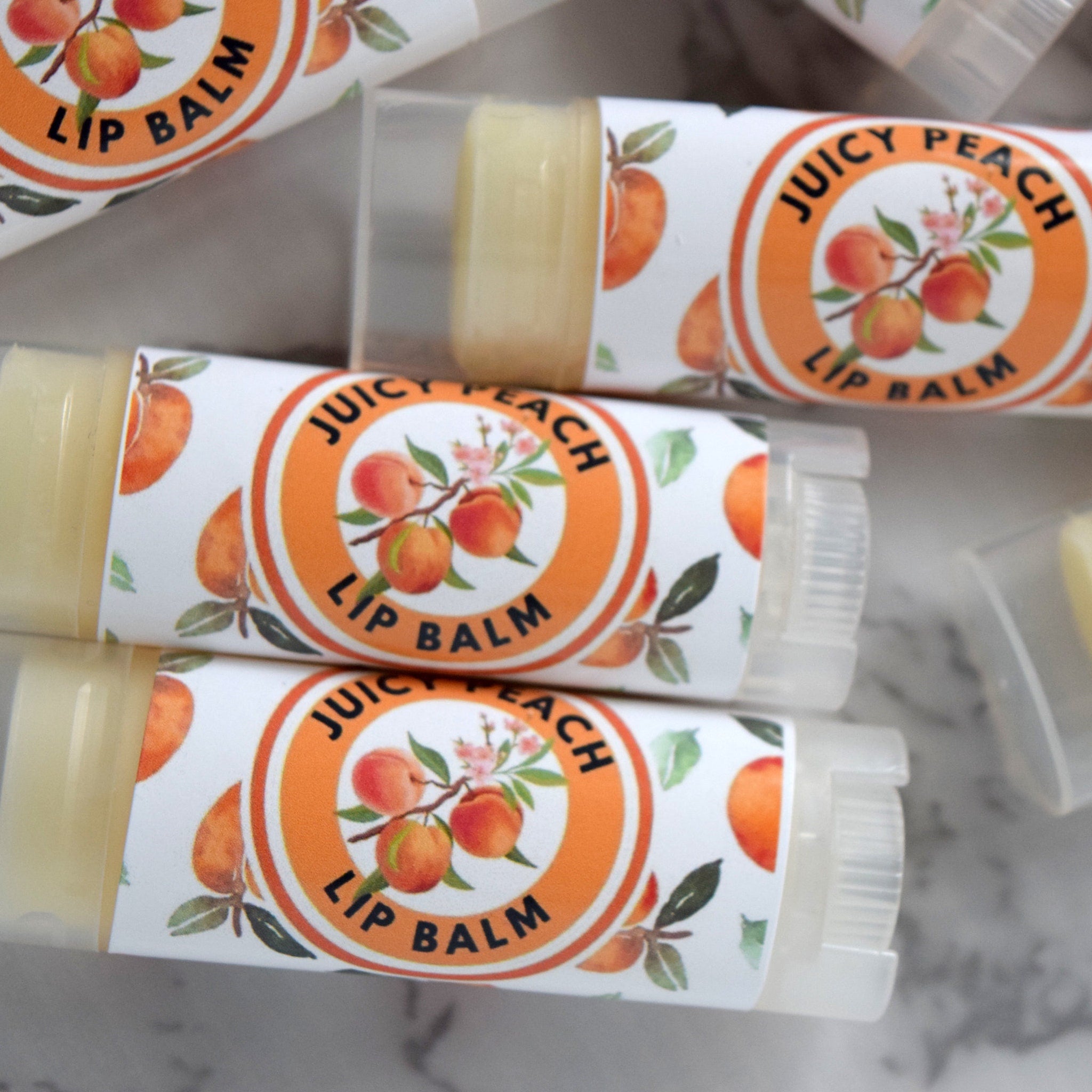 Lip balm tubes with peach label, clear plastic, and "Juicy Peach Lip Balm" text.