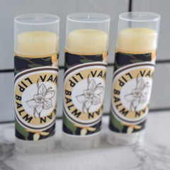 Lip balm tubes with clear caps, yellow balm, and "VANILLA LIP BALM" label