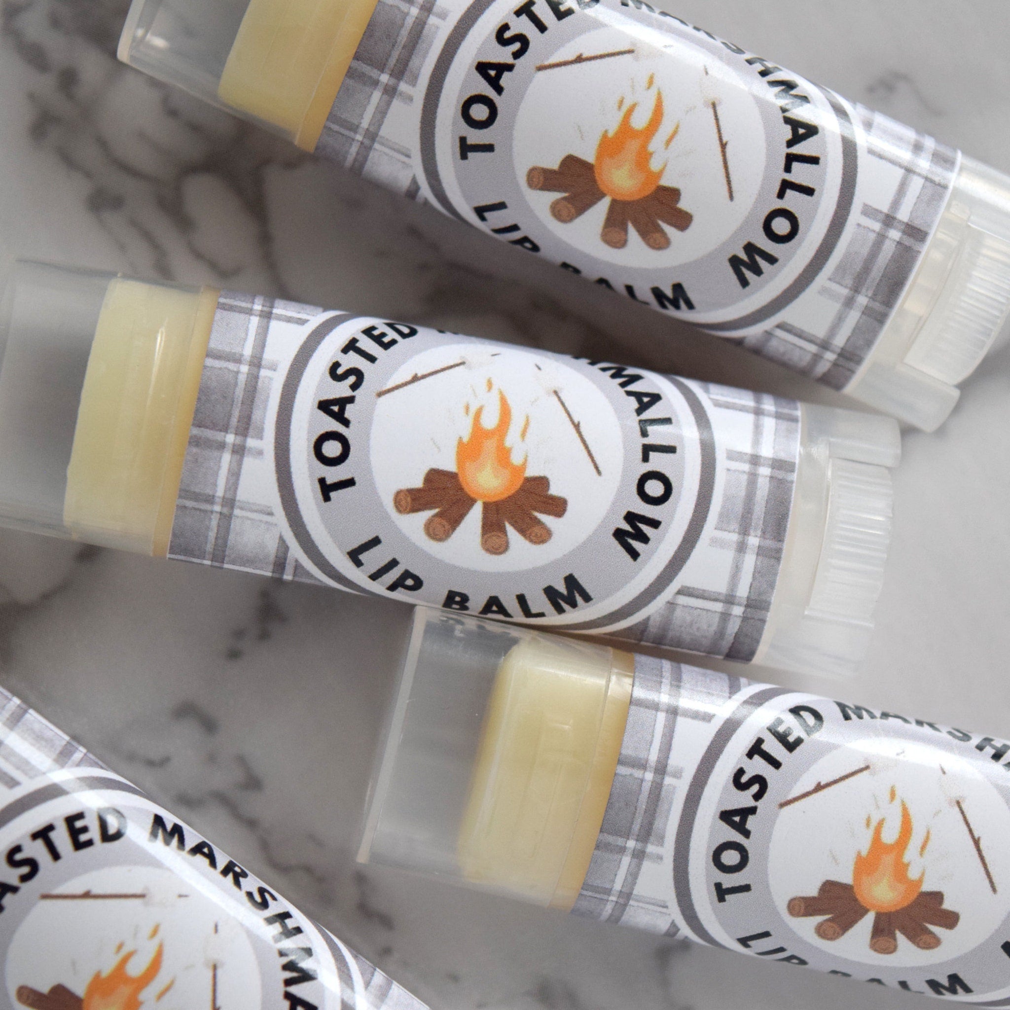 Lip balm tubes with clear plastic, yellow balm, and plaid pattern labels with text and illustration