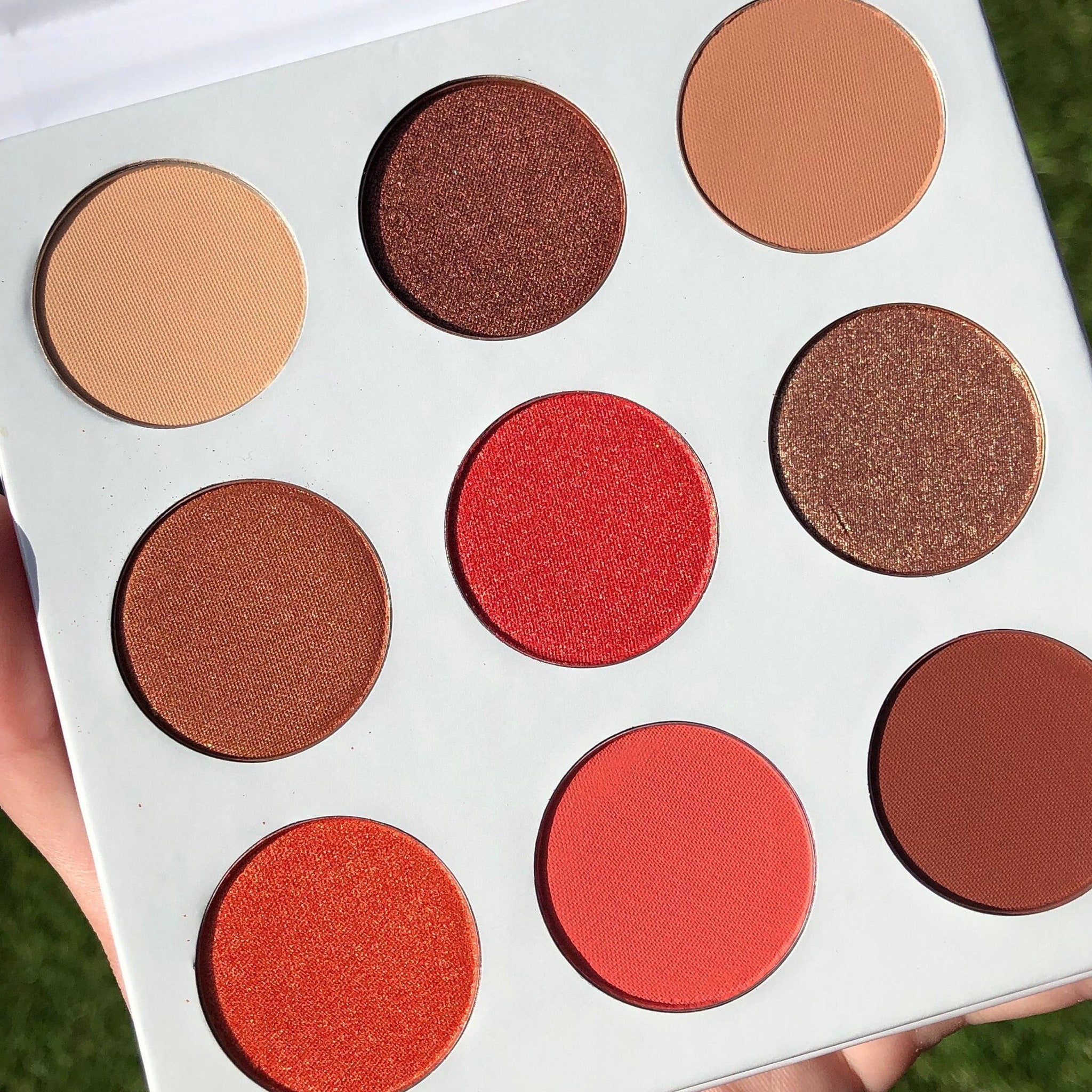 Side view of Red Daisies Eye Shadow Palette showing six vibrant matte and shimmer shades in circular pans with floral imprint.