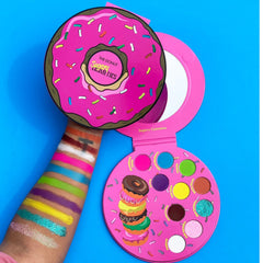 Close-up of fingertips applying shimmering bronze eye shadow from the Donut Palette onto eyelid