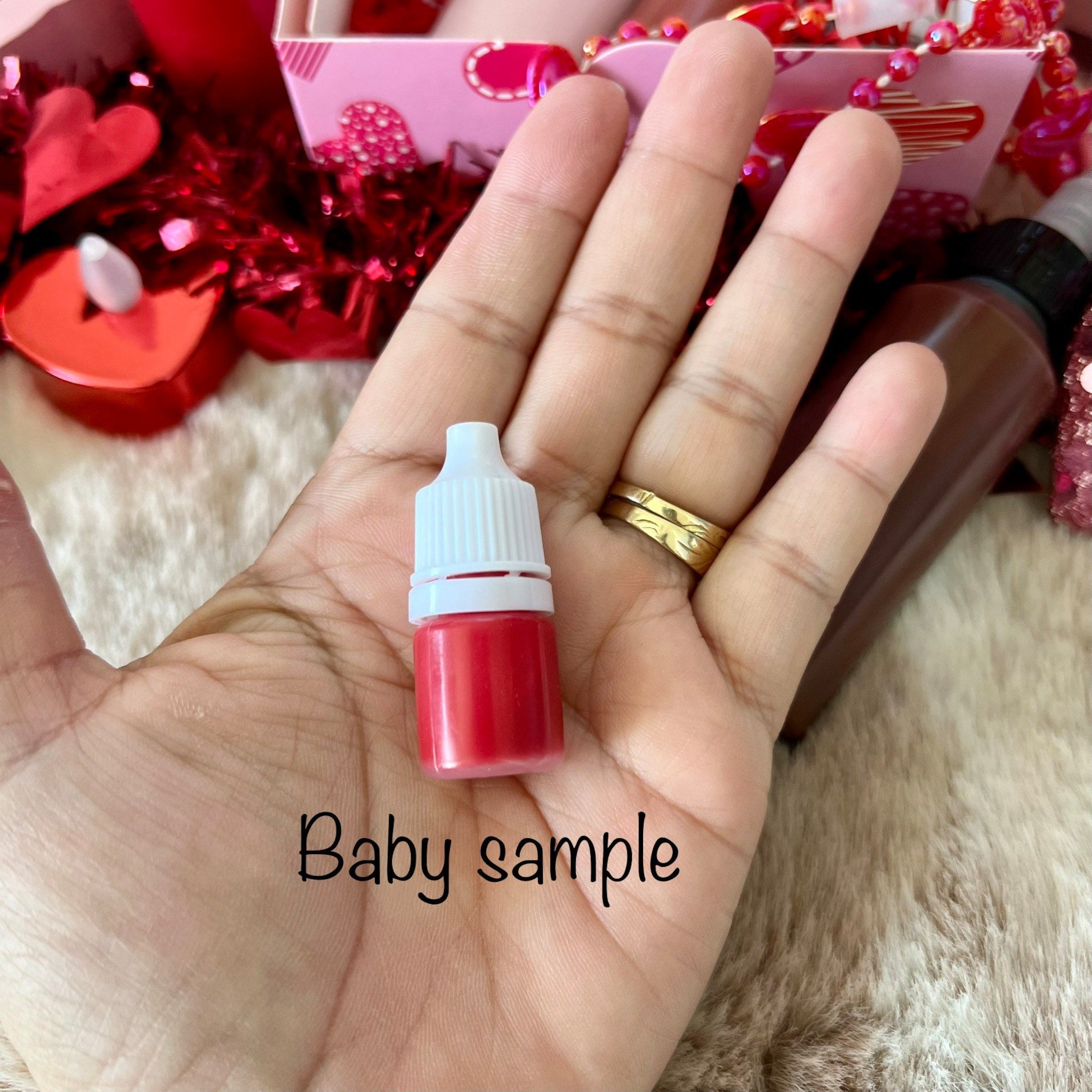 Red liquid sample in a small plastic bottle with white cap, held in hand