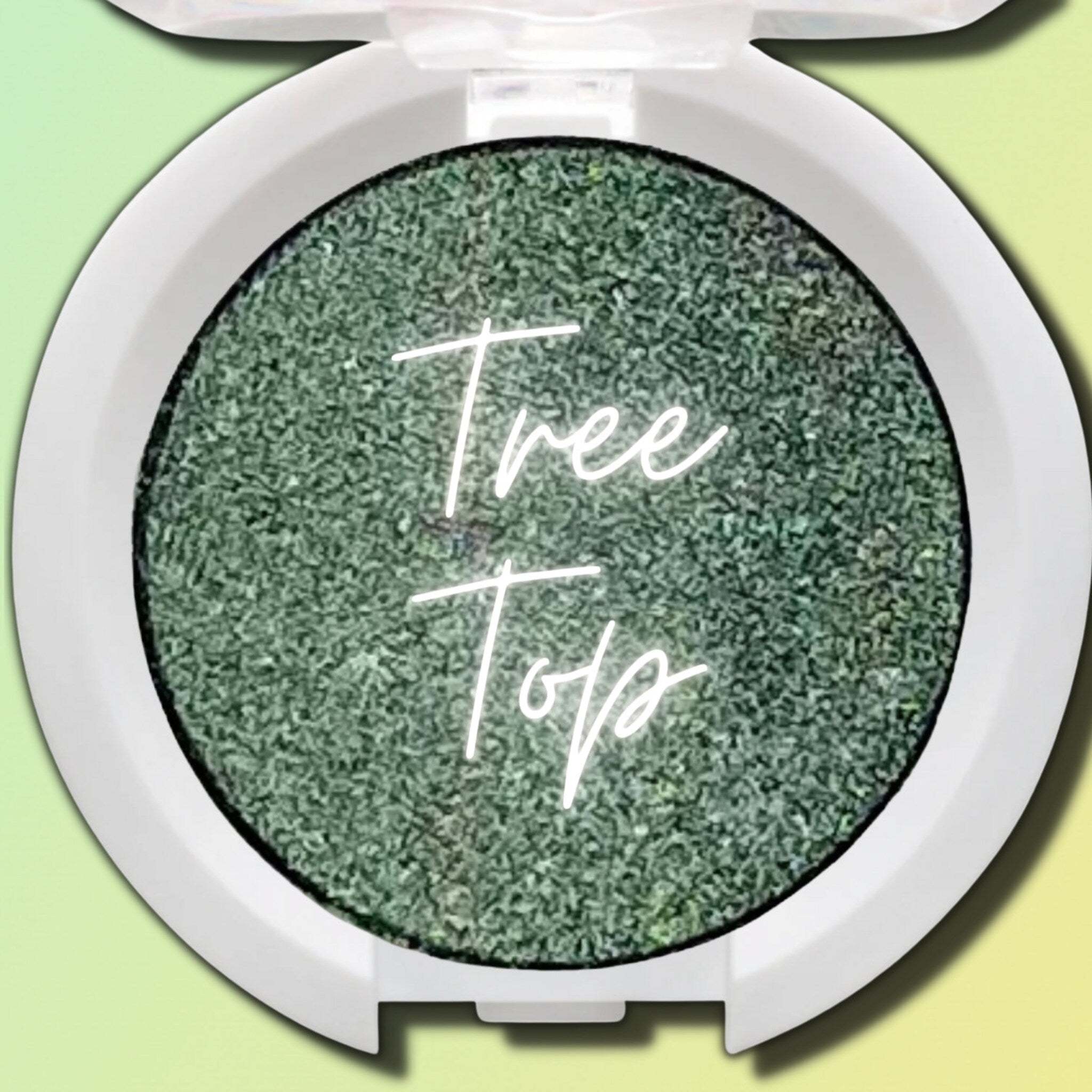 Close-up of a makeup brush applying vegan pressed eyeshadow in a compact pan, showing smooth pigment blend.