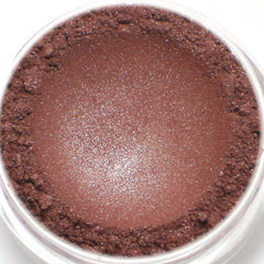 Side view of burgundy red shimmer vegan eyeshadow pot with rose gold lid catching light
