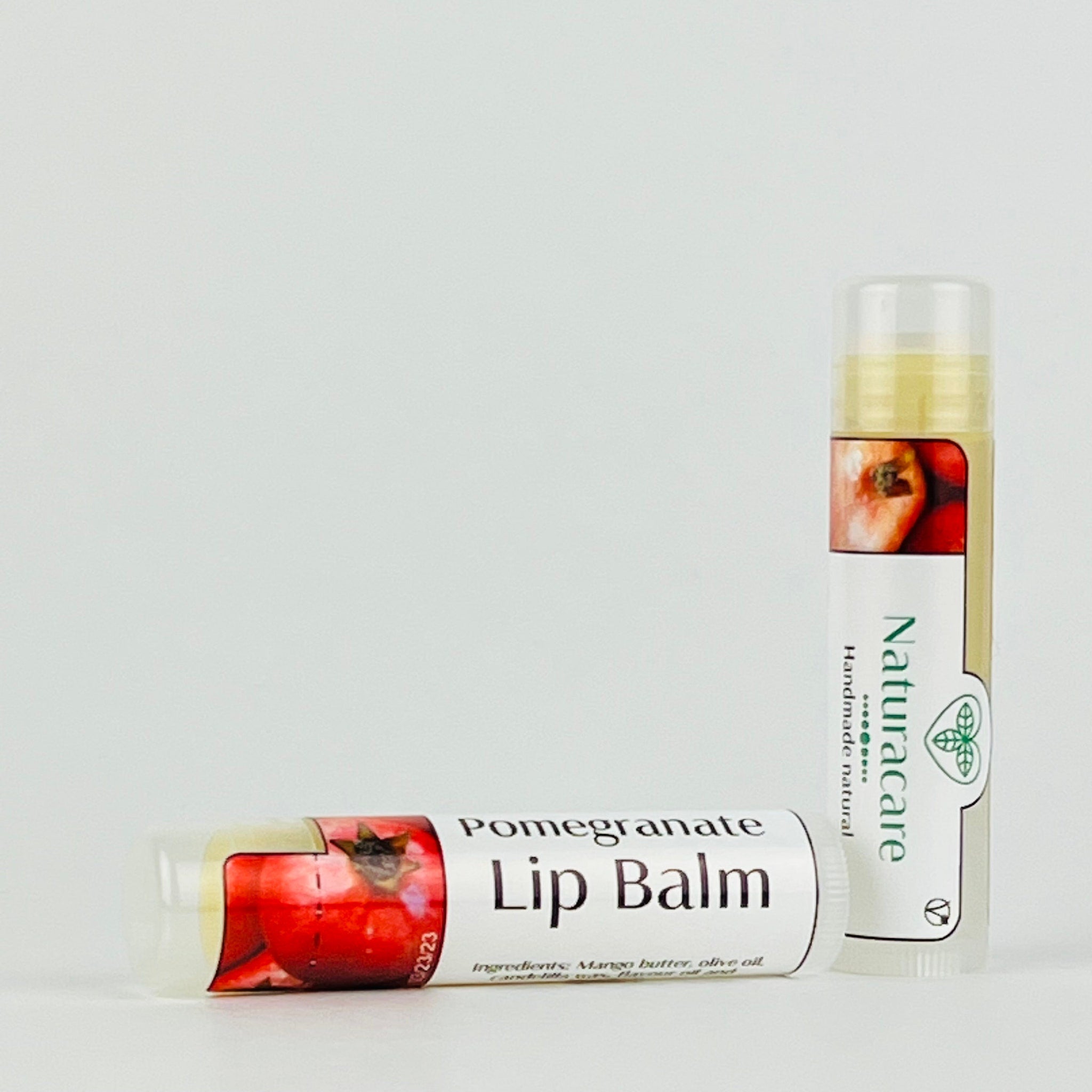 Lip balm tubes with red pomegranate image, white label, and Naturacare brand text