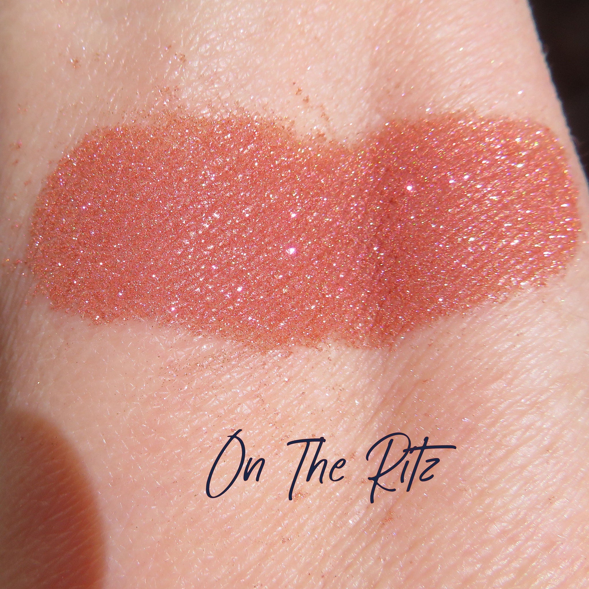 Side view of loose shimmering orange-pink-gold vegan mineral eye shadow pigment in a small jar