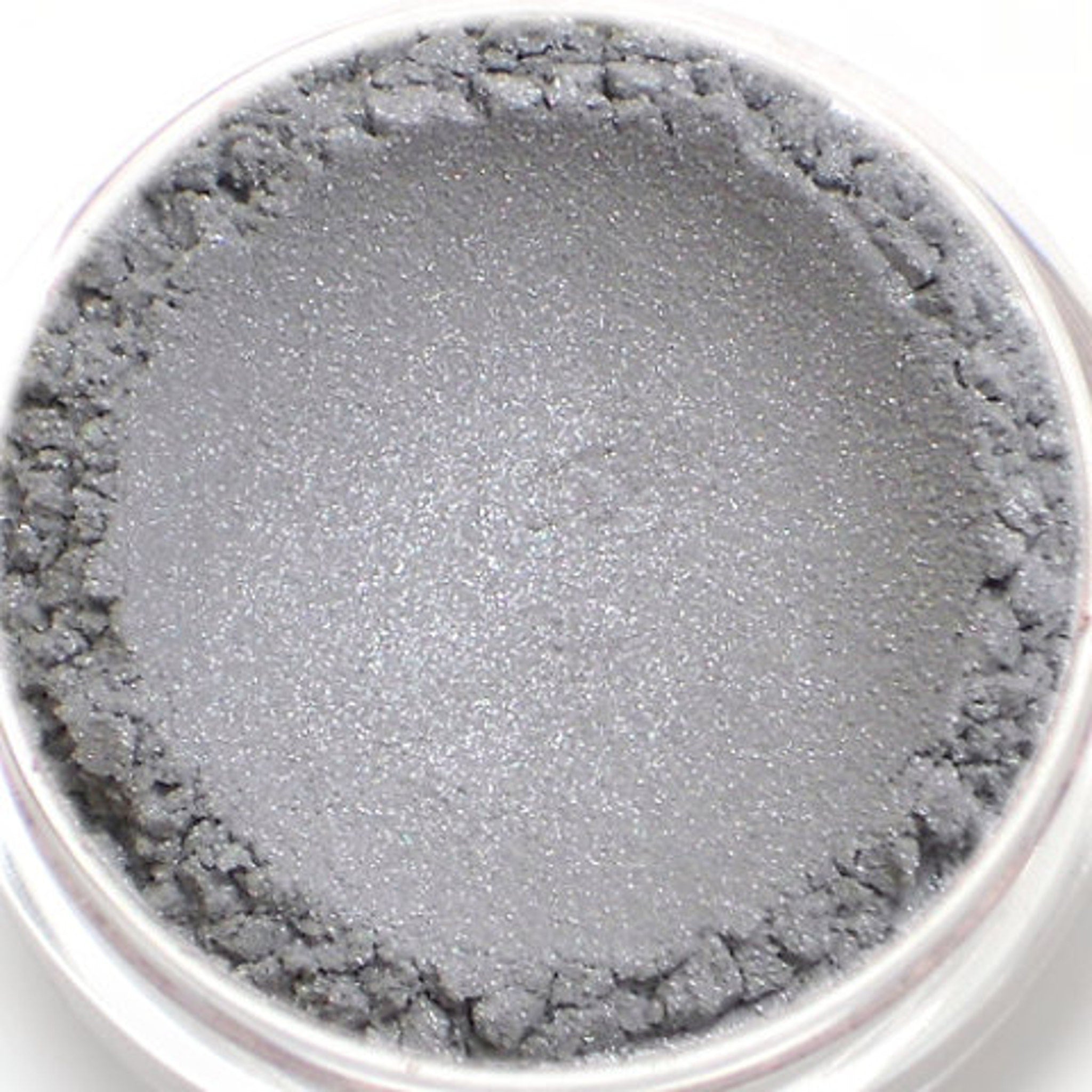 Side view of frosty silver-gray eyeshadow pan with lavender shimmer, showcasing mineral texture and vegan makeup details