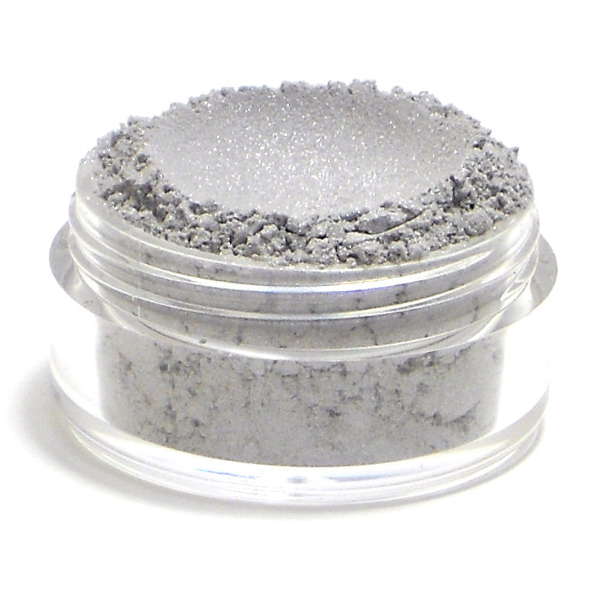 Side angle of frosty silver-gray eyeshadow pan with lavender shimmer, showcasing mineral texture