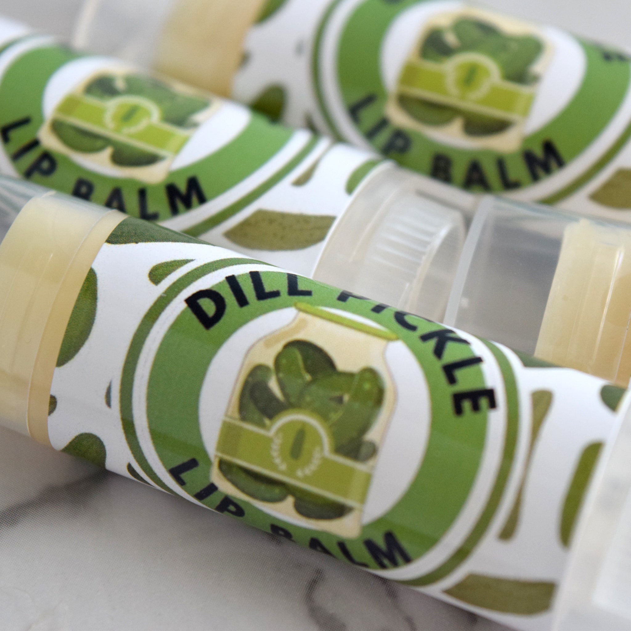 Lip balm tubes with green and white labels, "Dill Pickle" text, and clear plastic caps