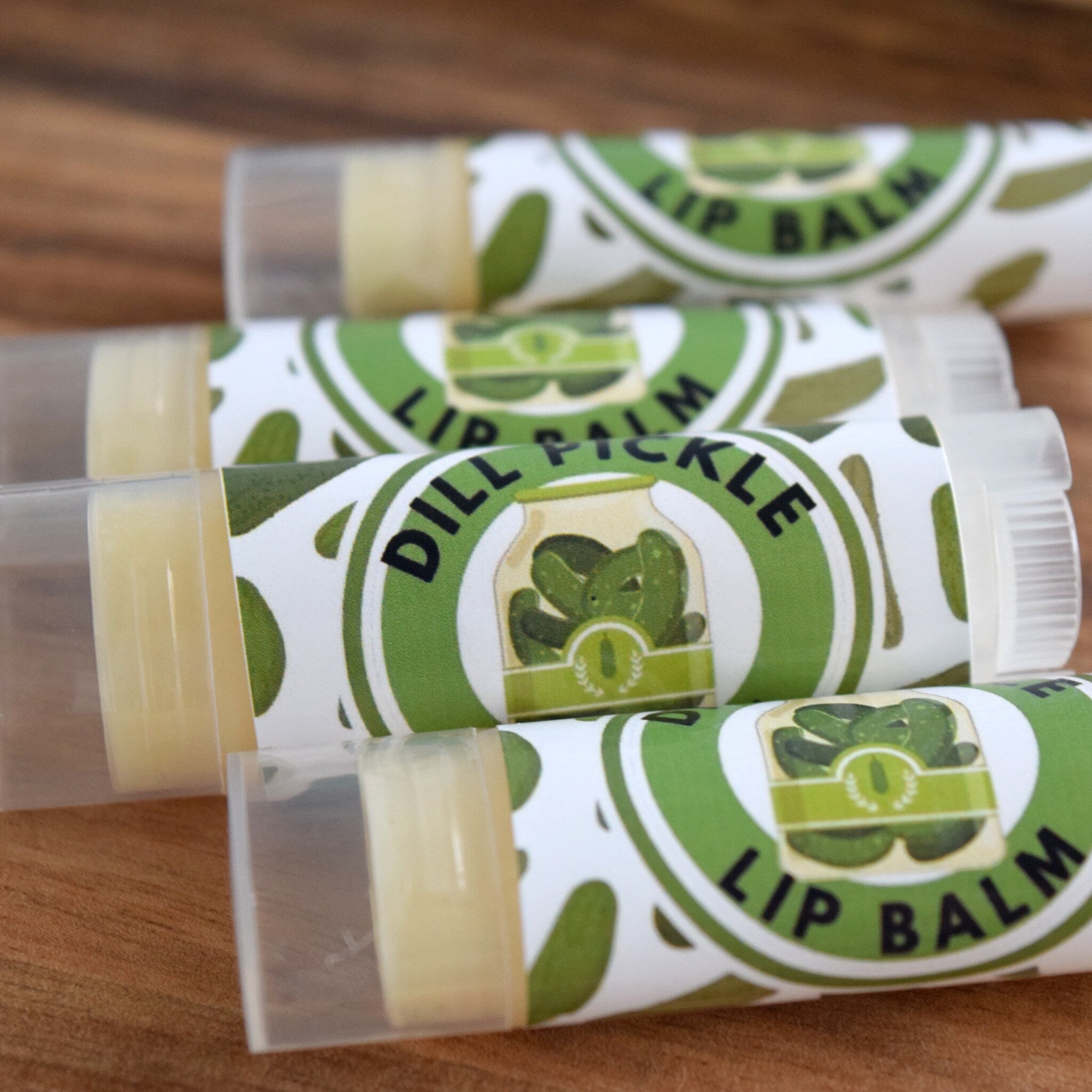 Lip balm tubes with green and white labels, clear plastic, and yellow balm inside