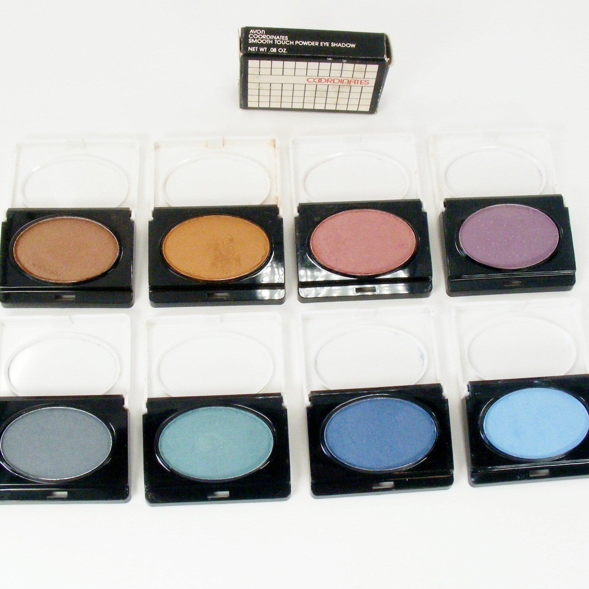 Powder eye shadow with various colors in black compacts, Avon brand visible
