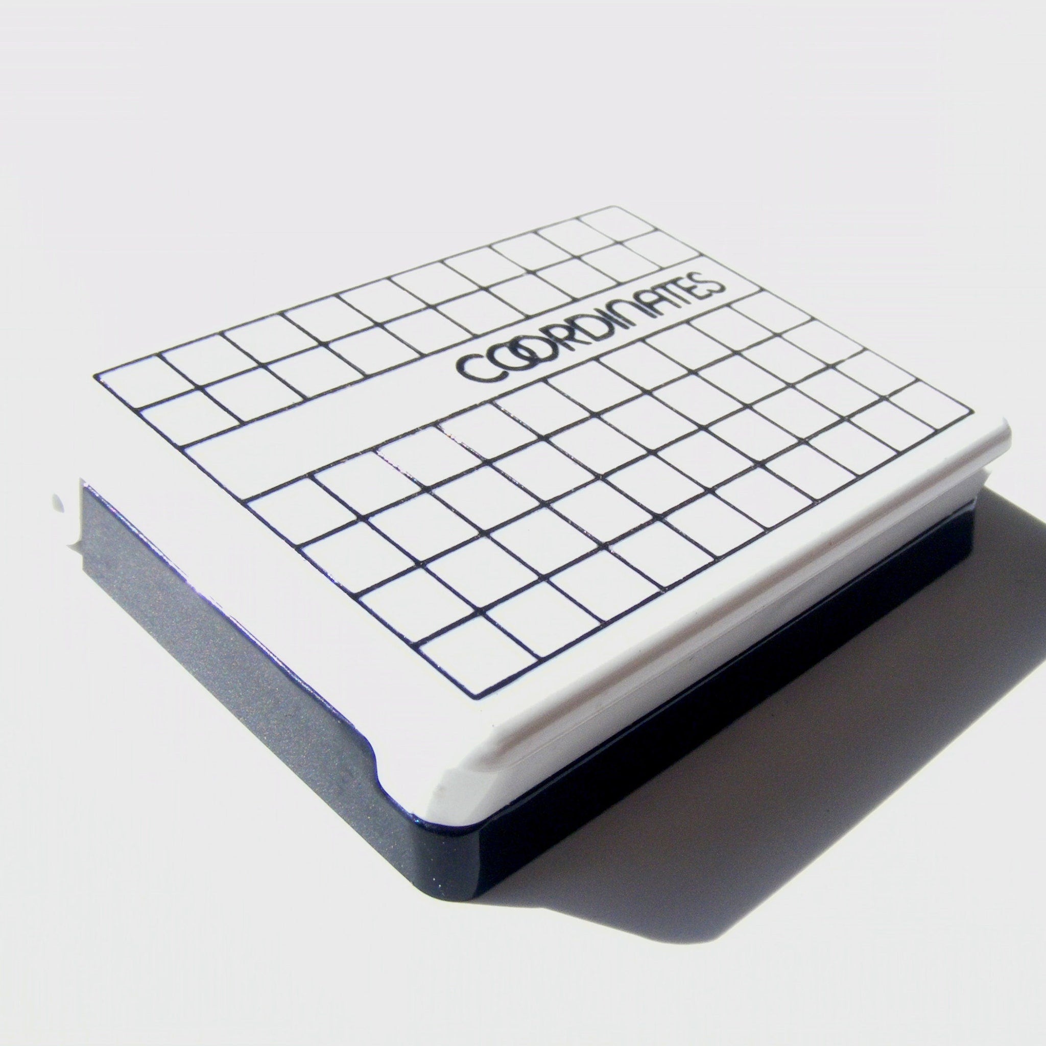 Grid notebook with white and black grid pattern, "COORDINATES" text on top, and black border